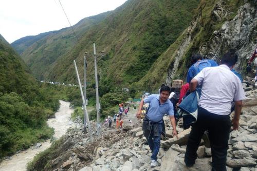 Algunas personas cruzan a pie el kilómetro 73 de la carretera Tarma-La Merced, que está bloqueado por deslizamiento.