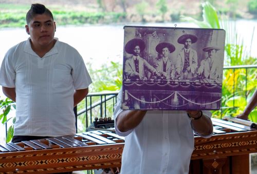 Un miembro de la familia muestra una foto de sus ancestros con una marimba