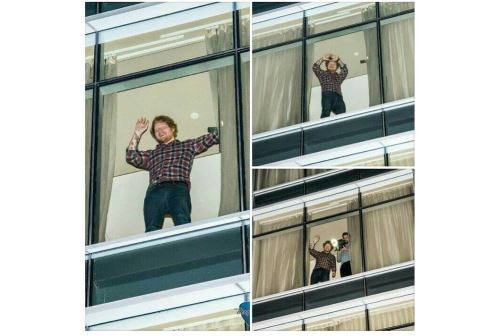 Ed Sheeran saluda a sus fans desde el balcón del hotel.