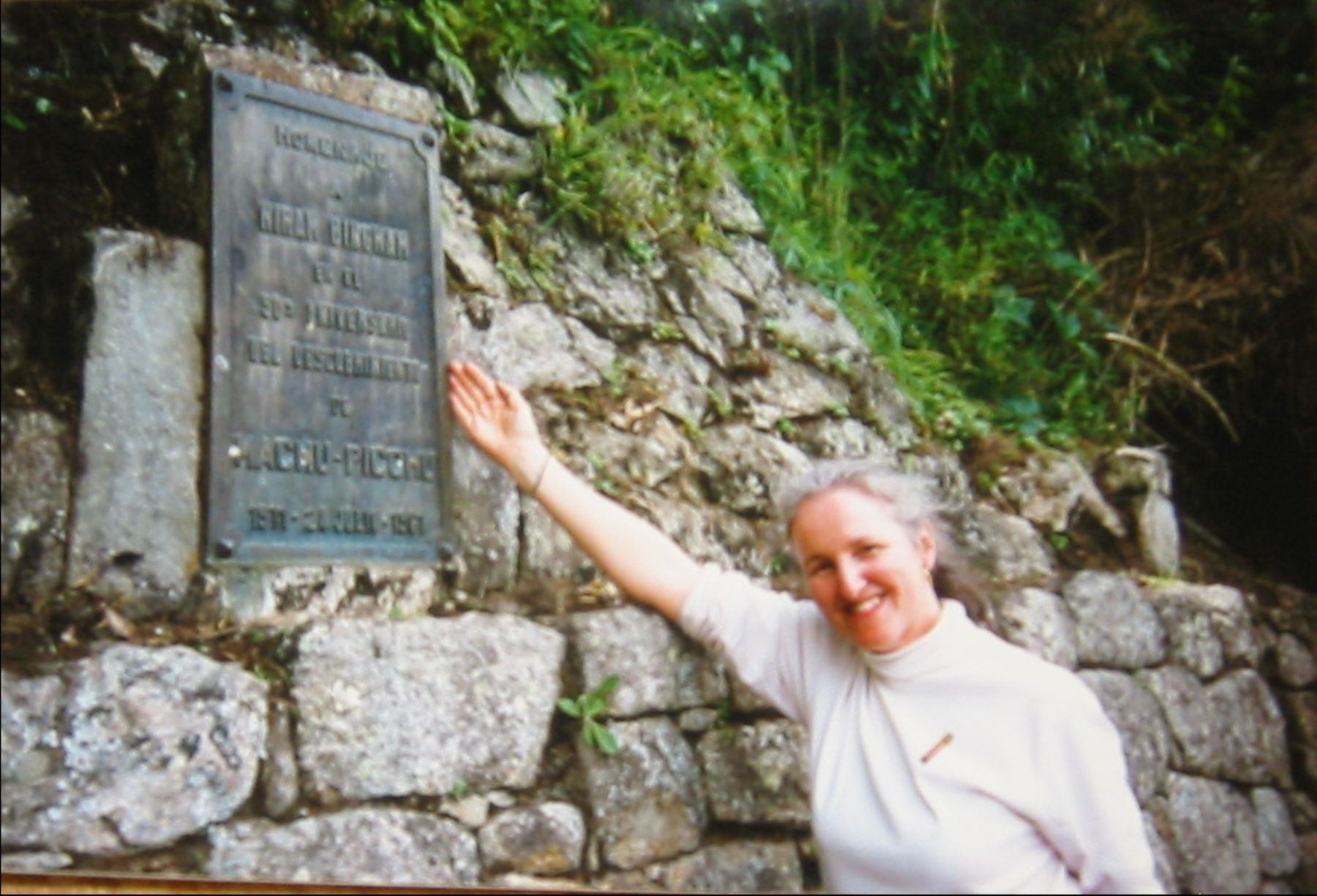 Abigail Bingham junto a la placa que recuerda a su abuelo, en la entrada a Machu Picchu.