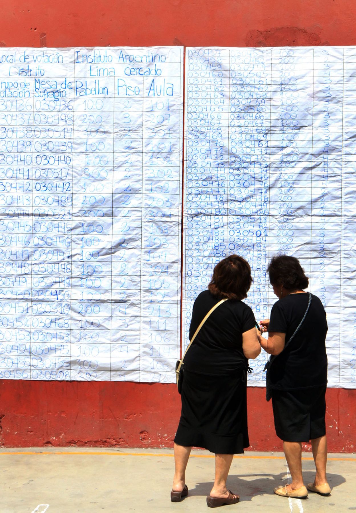 Dos electoras buscan su mesa de votación en un gran panel. 
Foto: ANDINA/Carlos Lezama