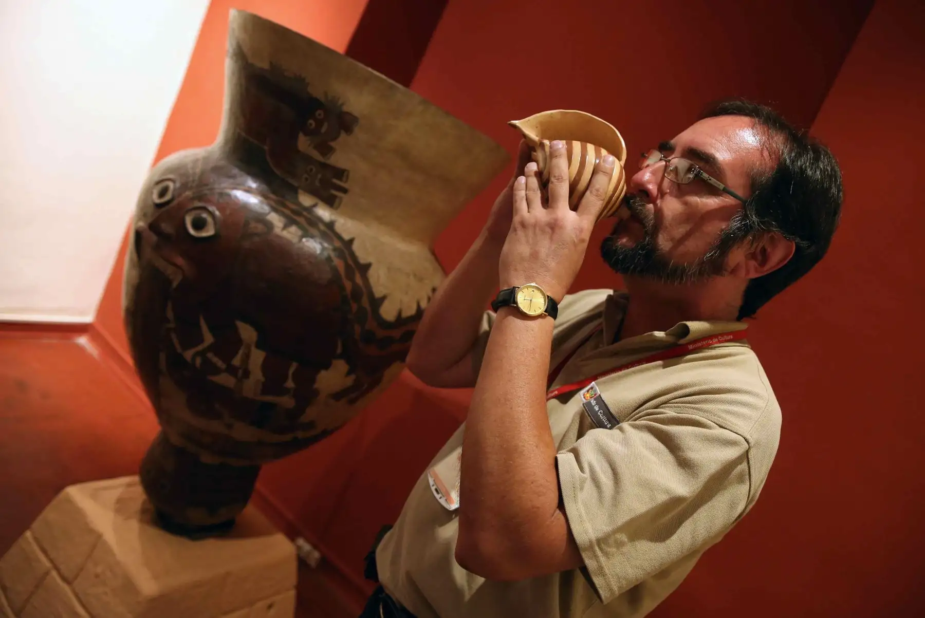 Investigador musical, Milano Trejo tocando un cerámica con forma de pututo en la exposición de la muestra Sonidos del Ande. Foto: EFE