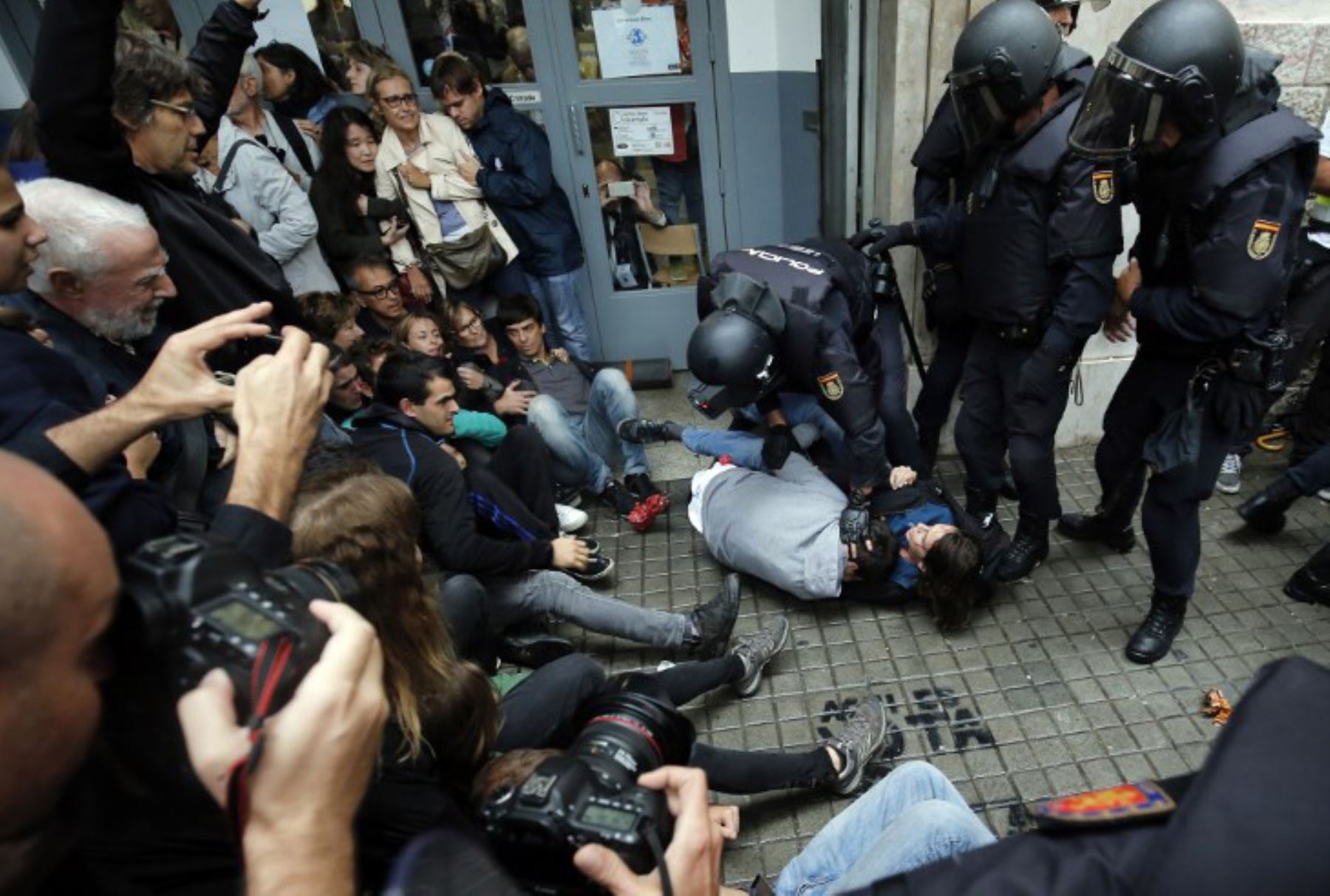 Agentes de policía españoles inmovilizan a algunas personas fuera de una mesa de votación en Barcelona. Foto: AFP