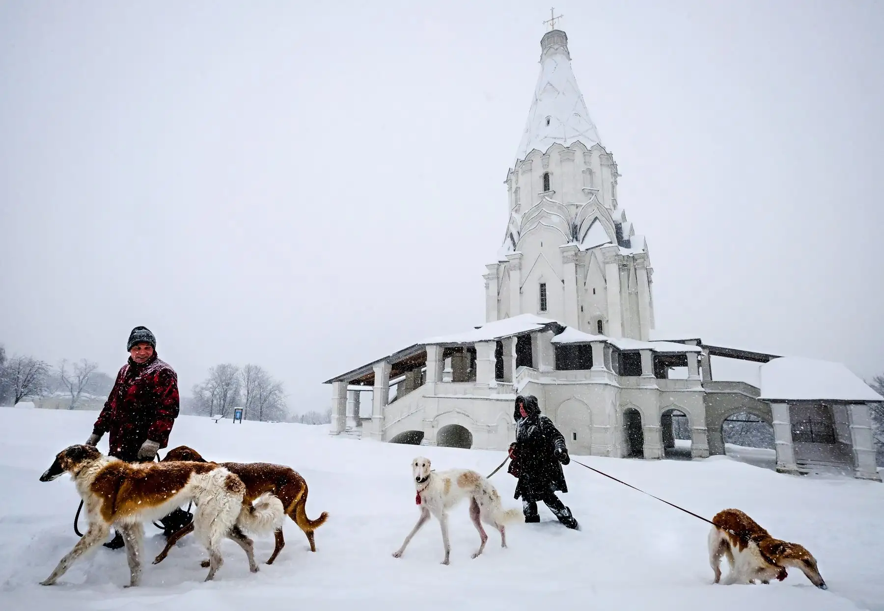 La gente pasea a sus perros cerca de una iglesia durante una nevada en Moscú. Foto: AFP