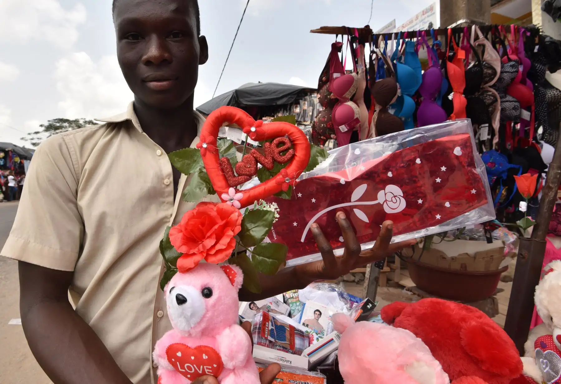 Un joven posa con artículos que compró para el Día de San Valentín en  Abidjan. Foto: AFP