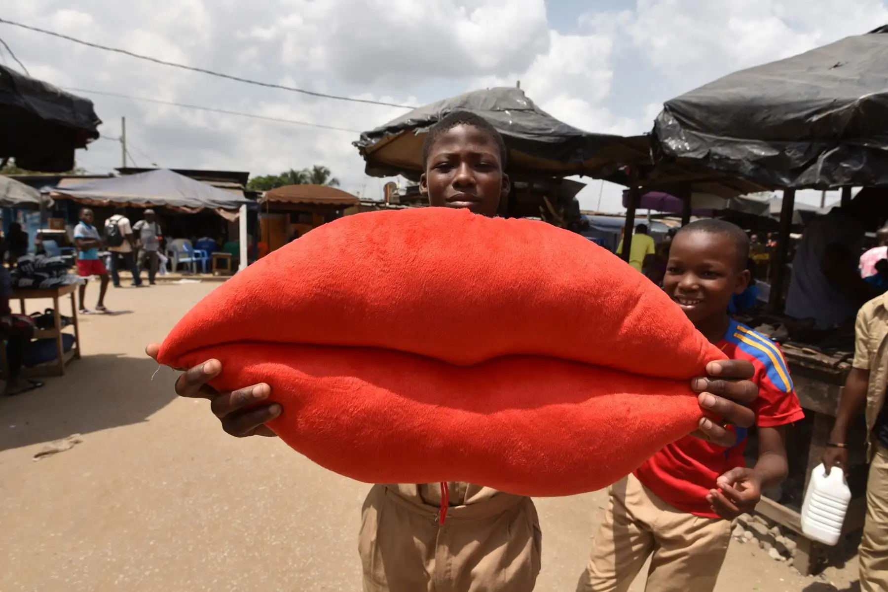 Un niño posa con una almohada en forma de labios a la venta por el Día de San Valentín en Yopougon. Foto: AFP