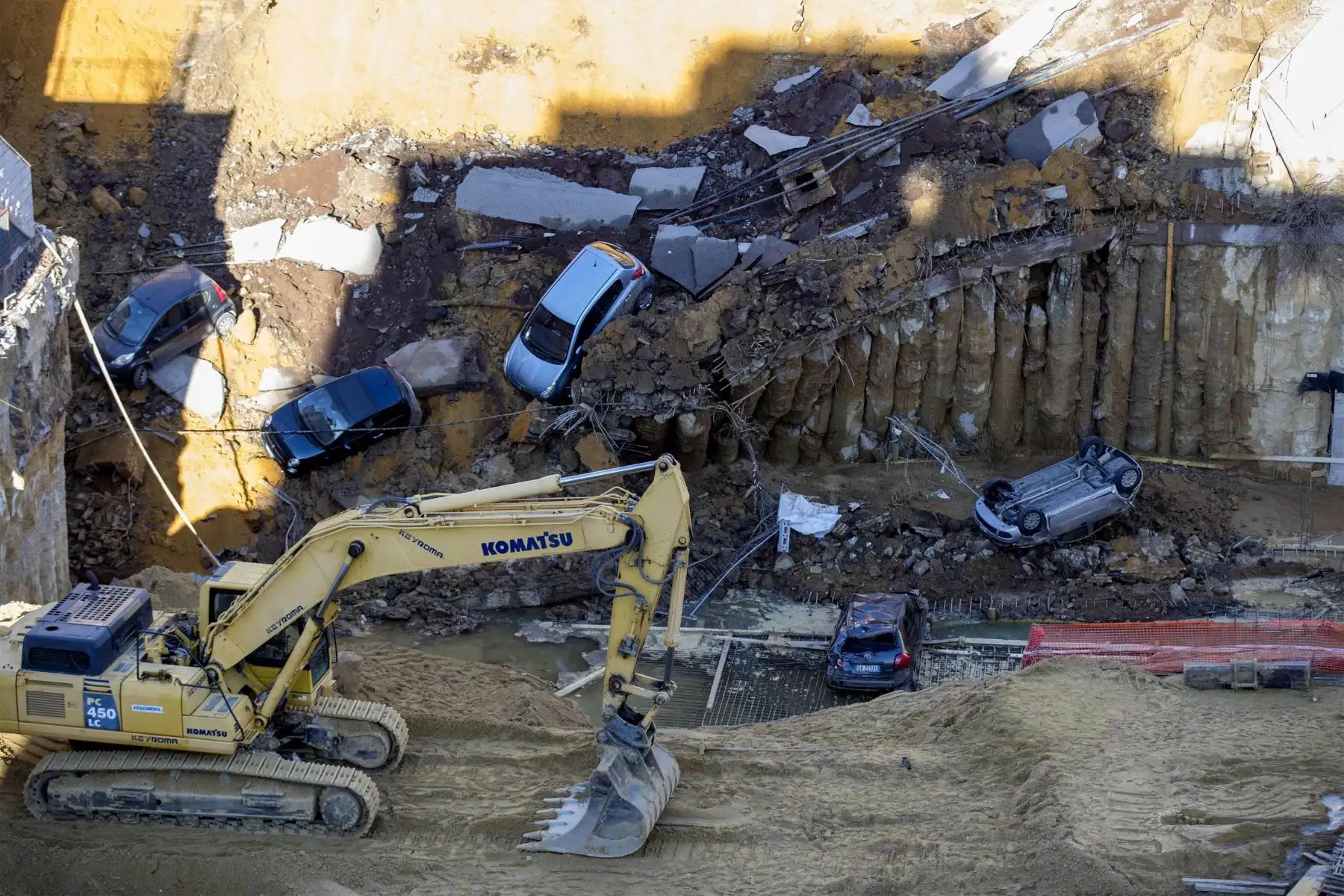 Una máquina excavadora despeja el terreno para remolcar un coche atrapado entre los escombros, en Roma. Foto: EFE.