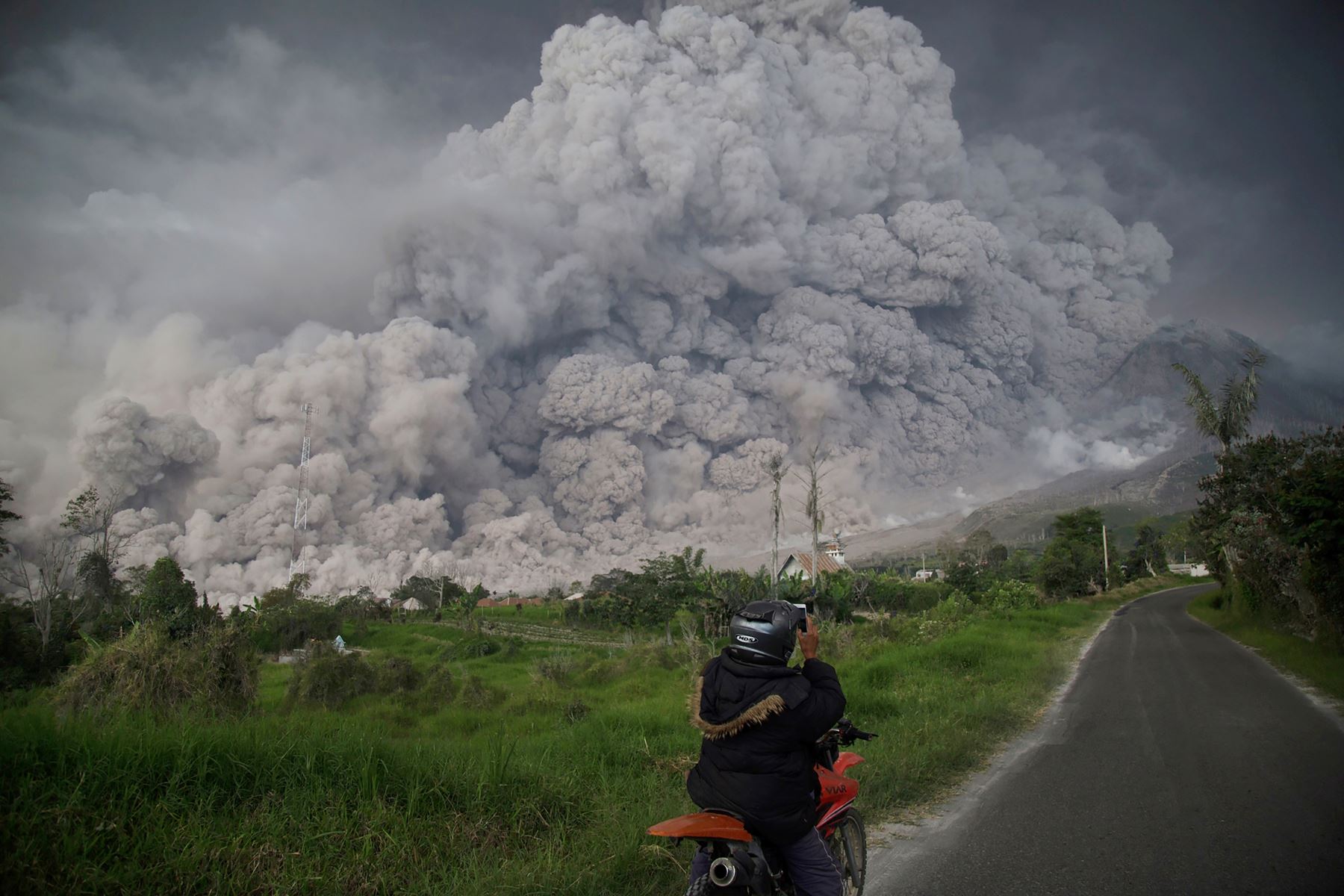 Un hombre indonesio toma una fotografía del volcán Sinabung mientras arroja ceniza volcánica. Foto: AFP