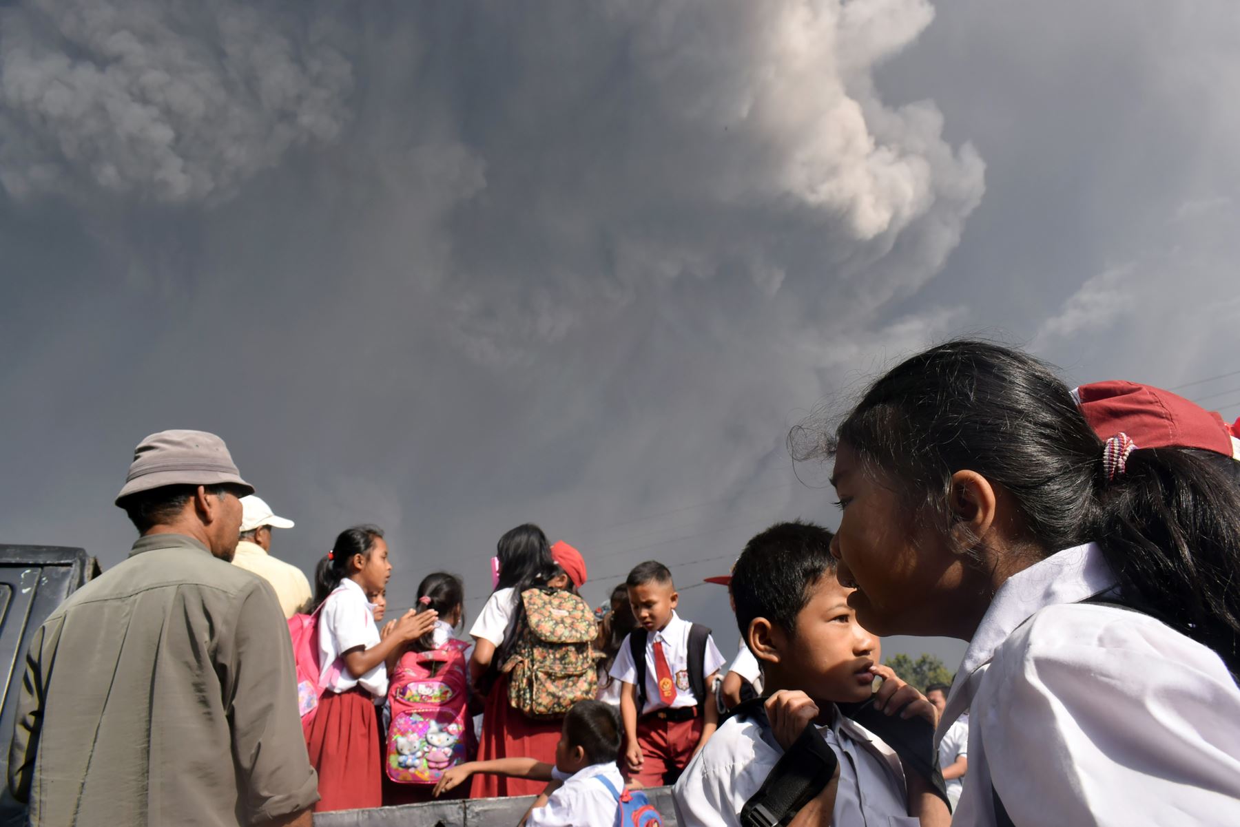 Escolares indonesios caminan mientras la espesa ceniza volcánica del volcán Sinabung se eleva en el aire después de otra erupción. Foto: AFP