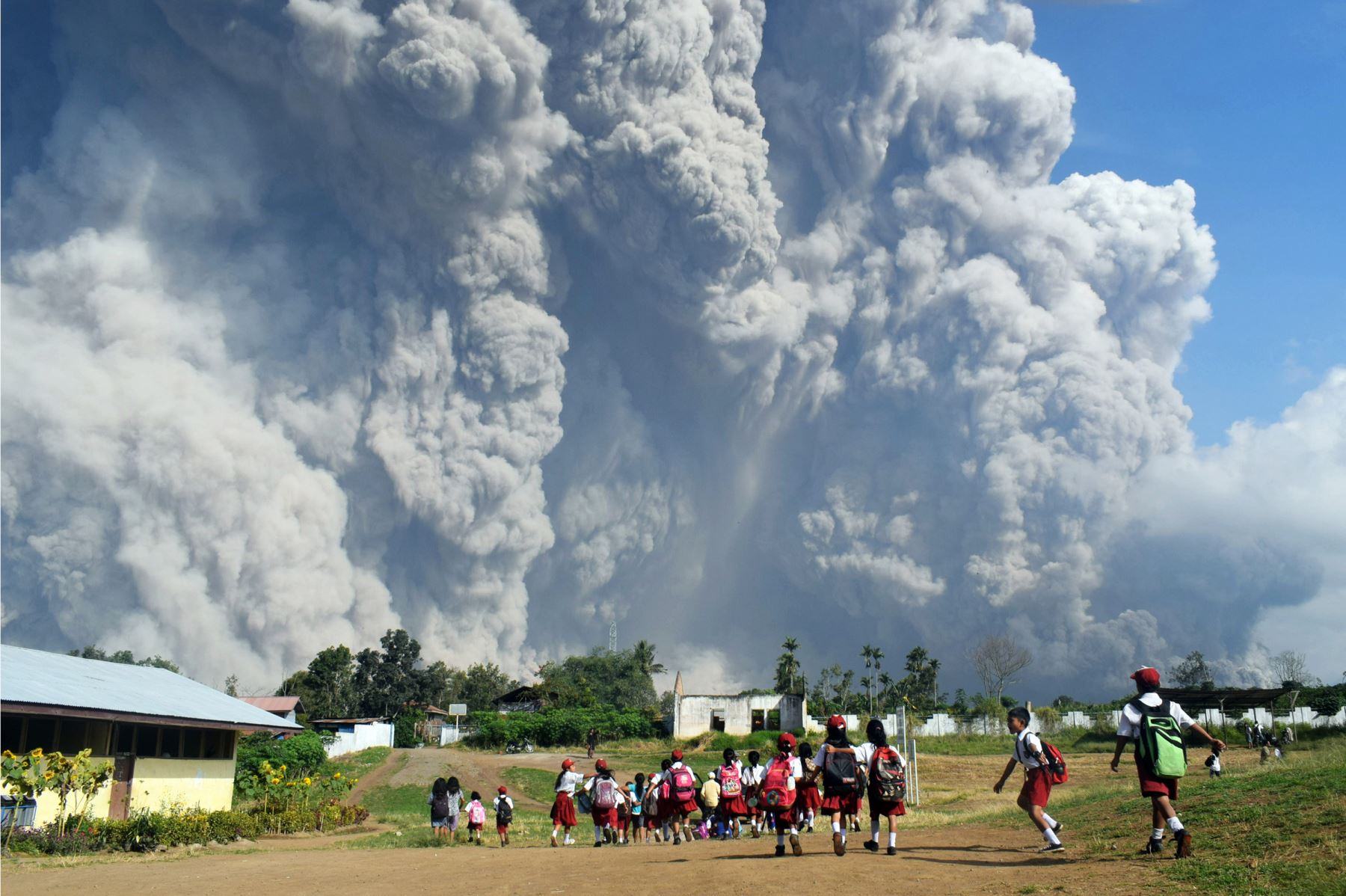 Escolares indonesios caminan mientras la espesa ceniza volcánica se eleva en el aire después de otra erupción. Foto: AFP