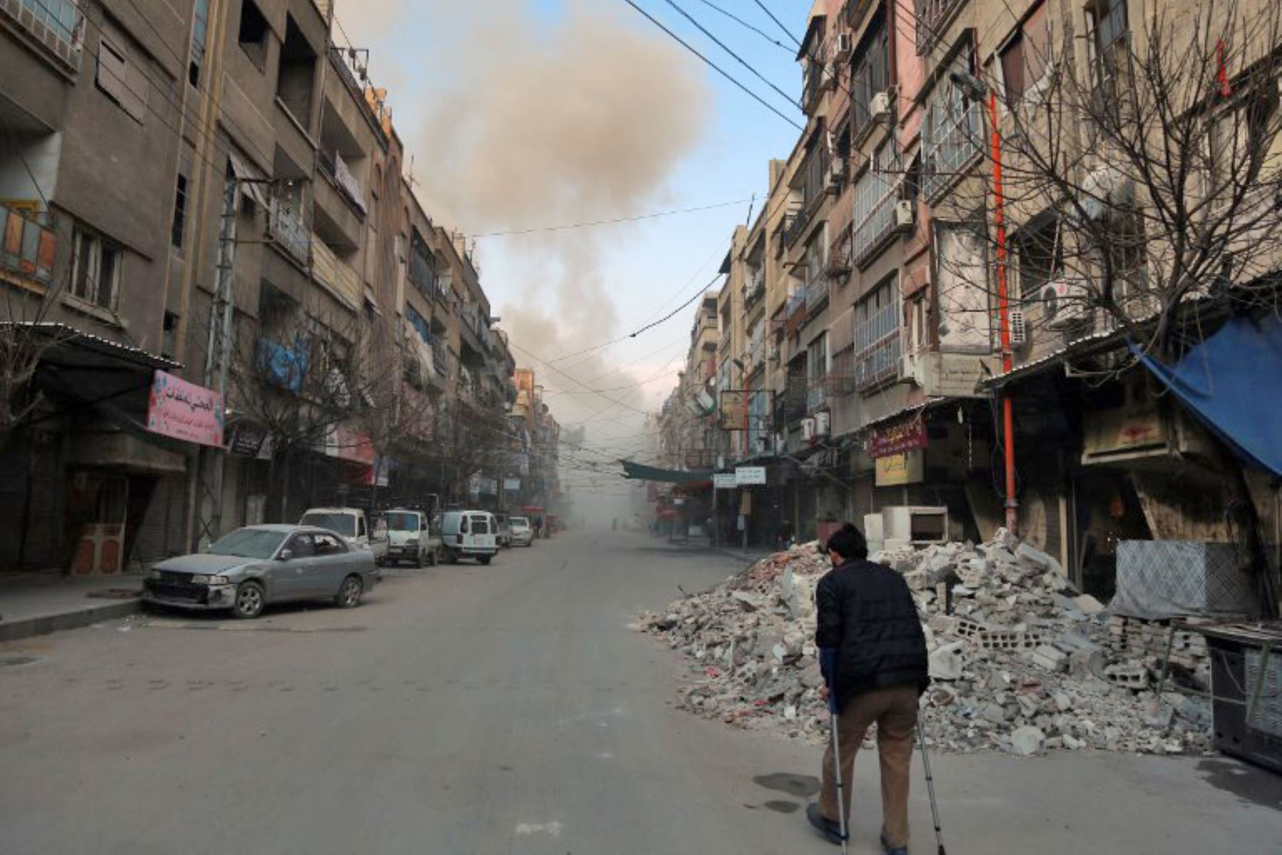 Un sirio con muletas camina por una calle en las afueras de la capital, Damasco, tras los ataques aéreos del Ejercito sirio. Foto: AFP