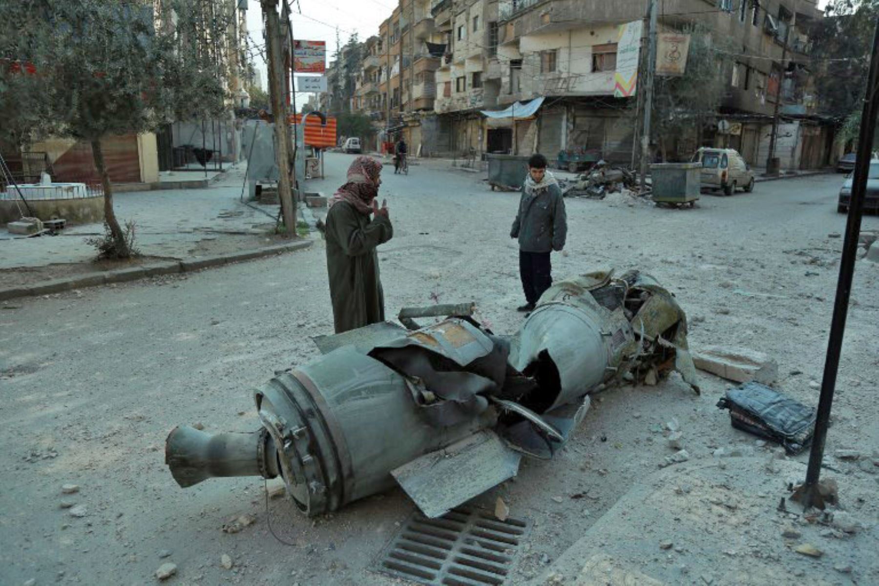 Hombres sirios pasan frente a los restos de un cohete en la ciudad de Douma, controlada por los rebeldes.Foto:AFP