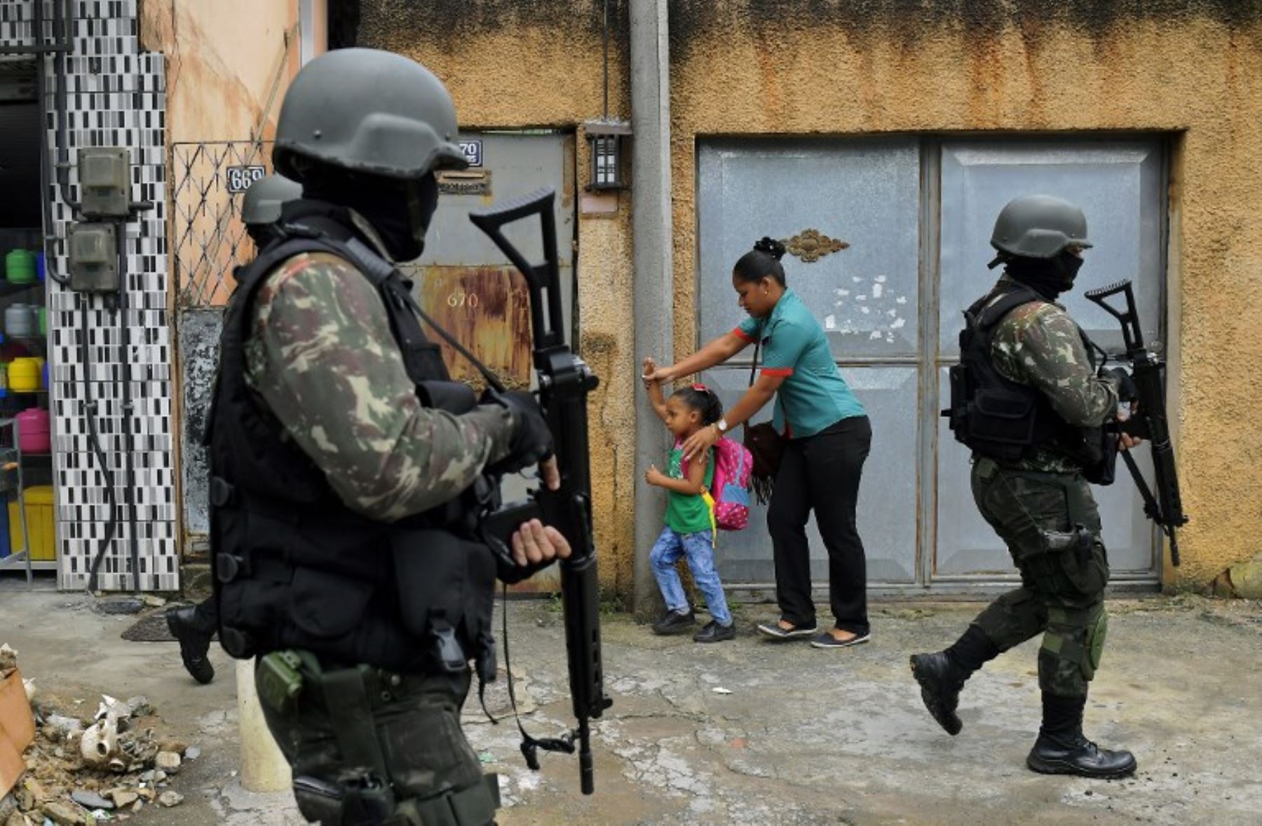 Una madre y su hijo caminan junto a la policía militar  que patrulla las calles de la favela de Vila Kennedy. Foto:AFP