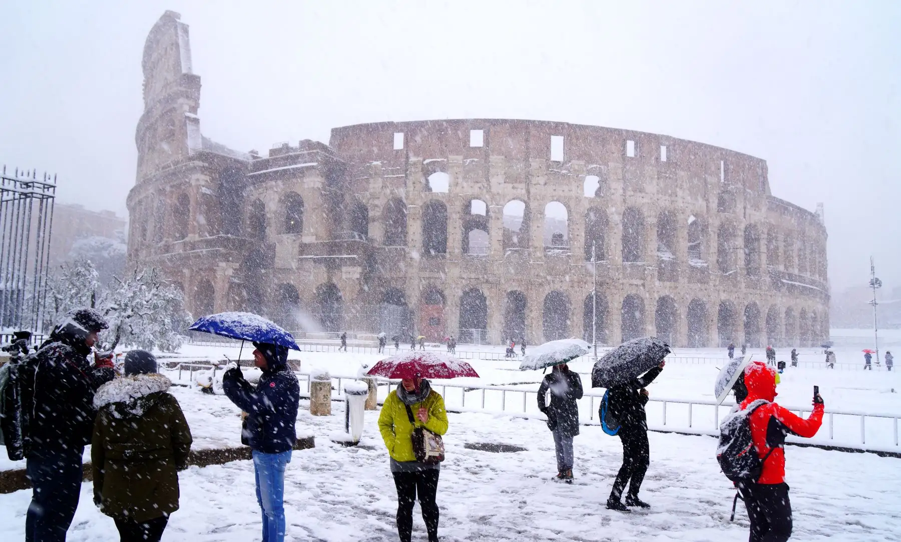 Turistas toman fotografías del coliseo romano durante una nevada. Foto: AFP