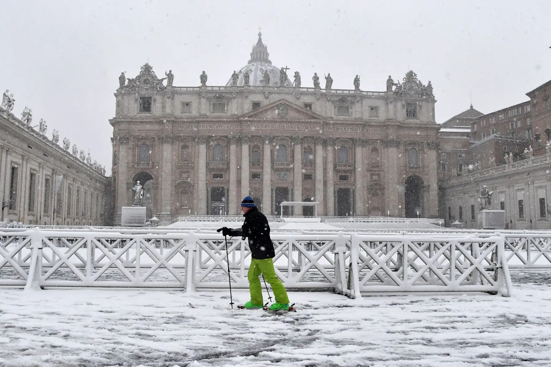 Un hombre con esquís camina cerca a la plaza de San Pedro cubierto de nieve. Foto: AFP