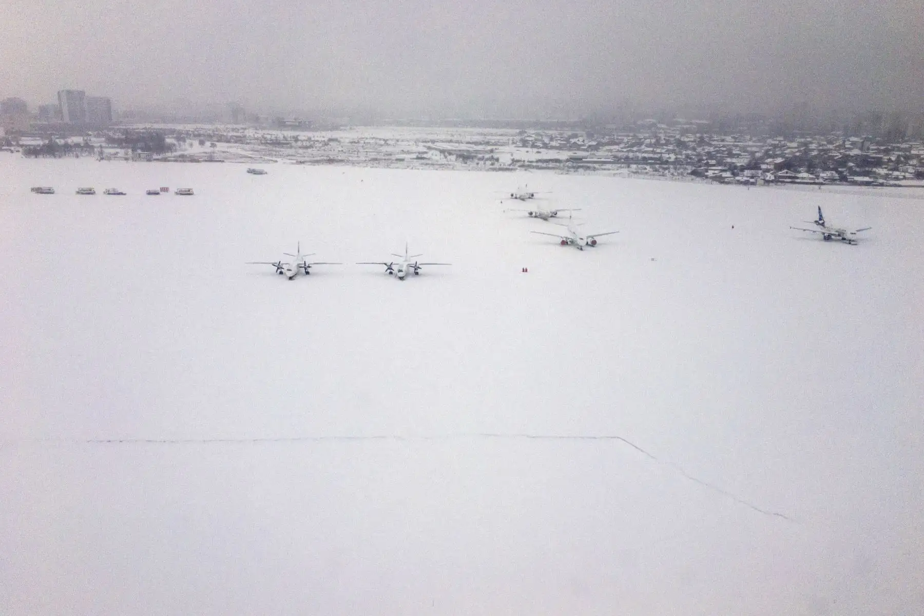 Fotografía tomada desde la ventana de un avión de aterrizaje muestra aviones cubiertos de nieve en la pista del aeropuerto de Sofía en Bulgaria. Foto: AFP