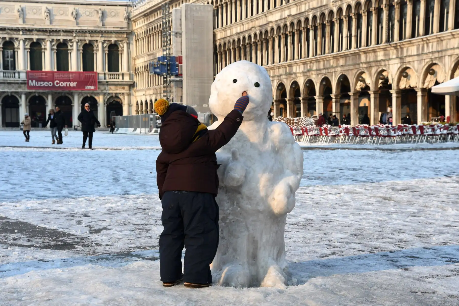 Un niño juega con un muñeco de nieve en la Plaza de San Marcos en Venecia. Foto: AFP