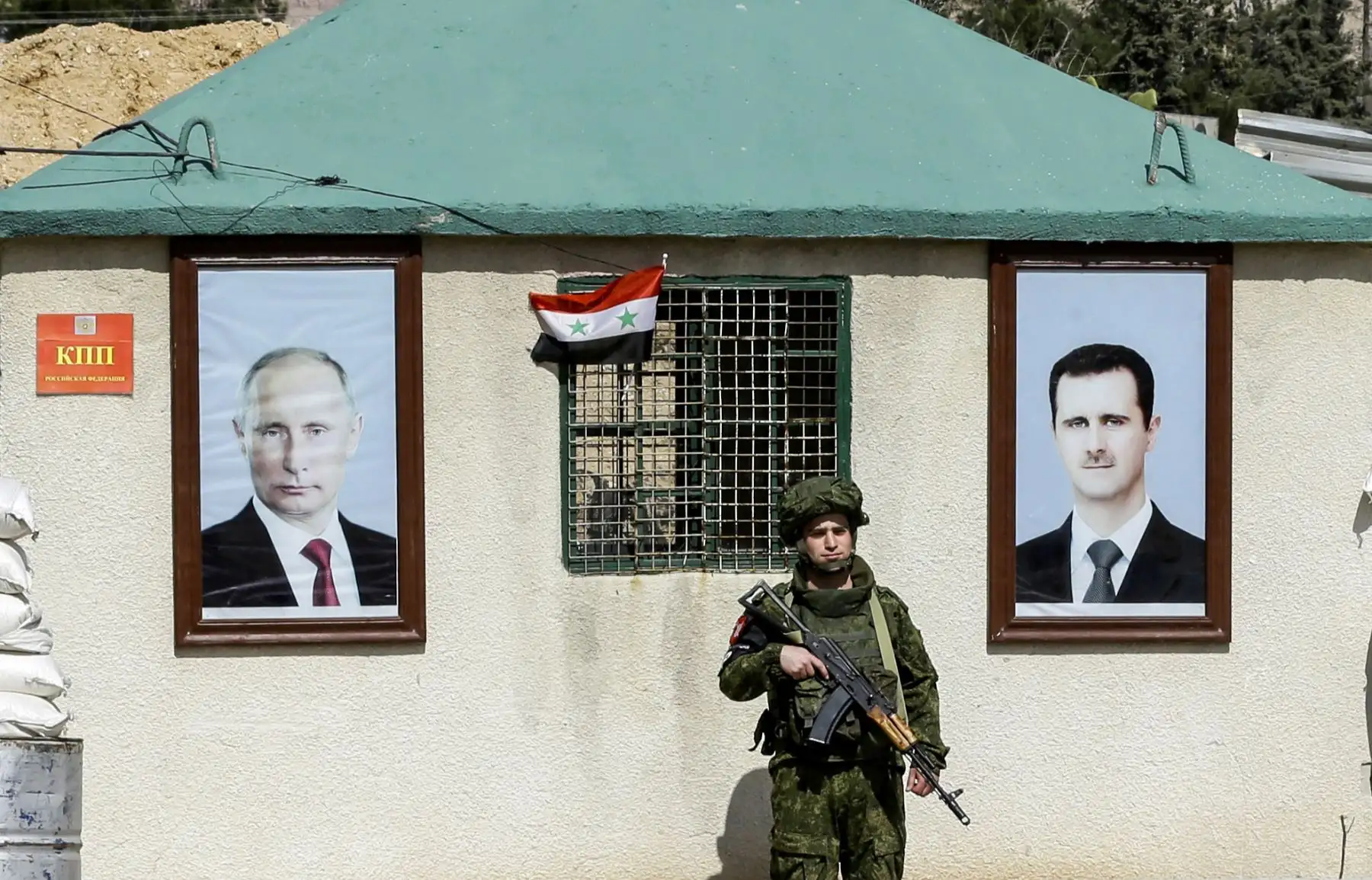 Miembro de la policía militar rusa montando guardia entre los retratos del presidente sirio Bashar al-Assad  y el presidente ruso Vladimir Putin, colgandos fuera de un puesto  de control Wafideen en las afueras de Damasco. AFP