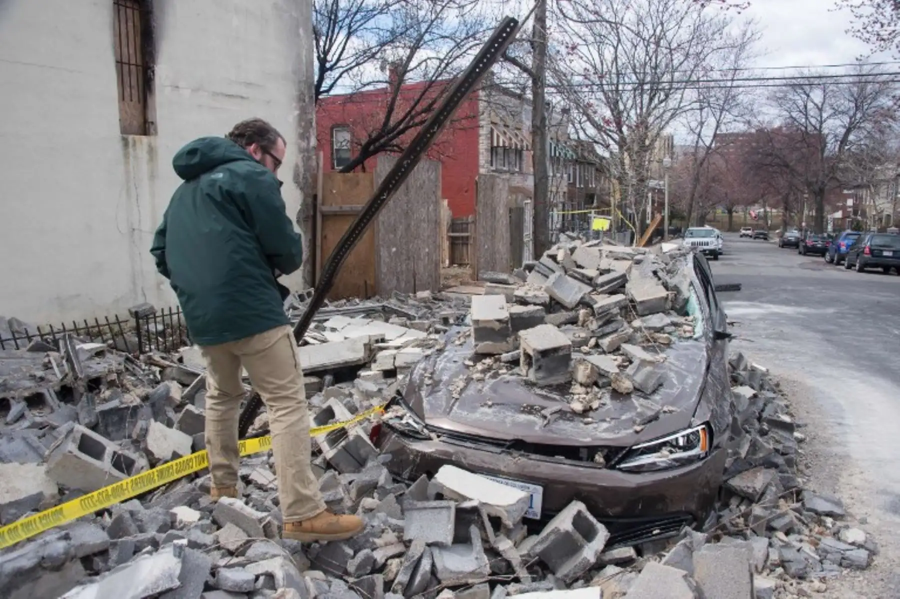 Un empleado de una compañía de seguros verifica el daño a un automóvil después de que un edificio parcialmente quemado se derrumbó debido a fuertes vientos en el noreste de Washington DC.Foto.AFP