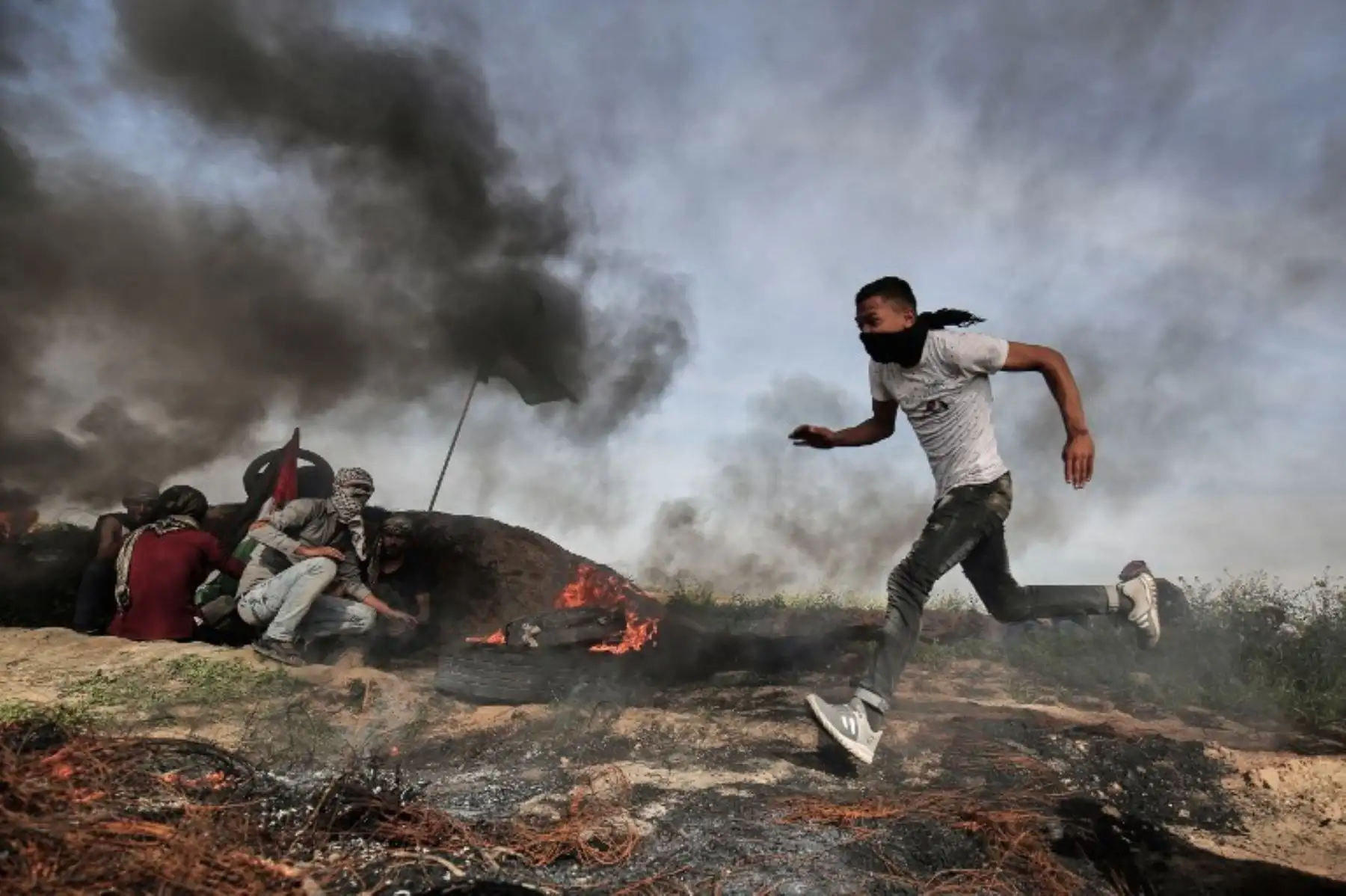 Un manifestante palestino corre para cubrirse con otros durante los enfrentamientos con las fuerzas israelíes cerca de Khan Yunis en la frontera entre Israel y la franja del sur de Gaza. Foto:AFP