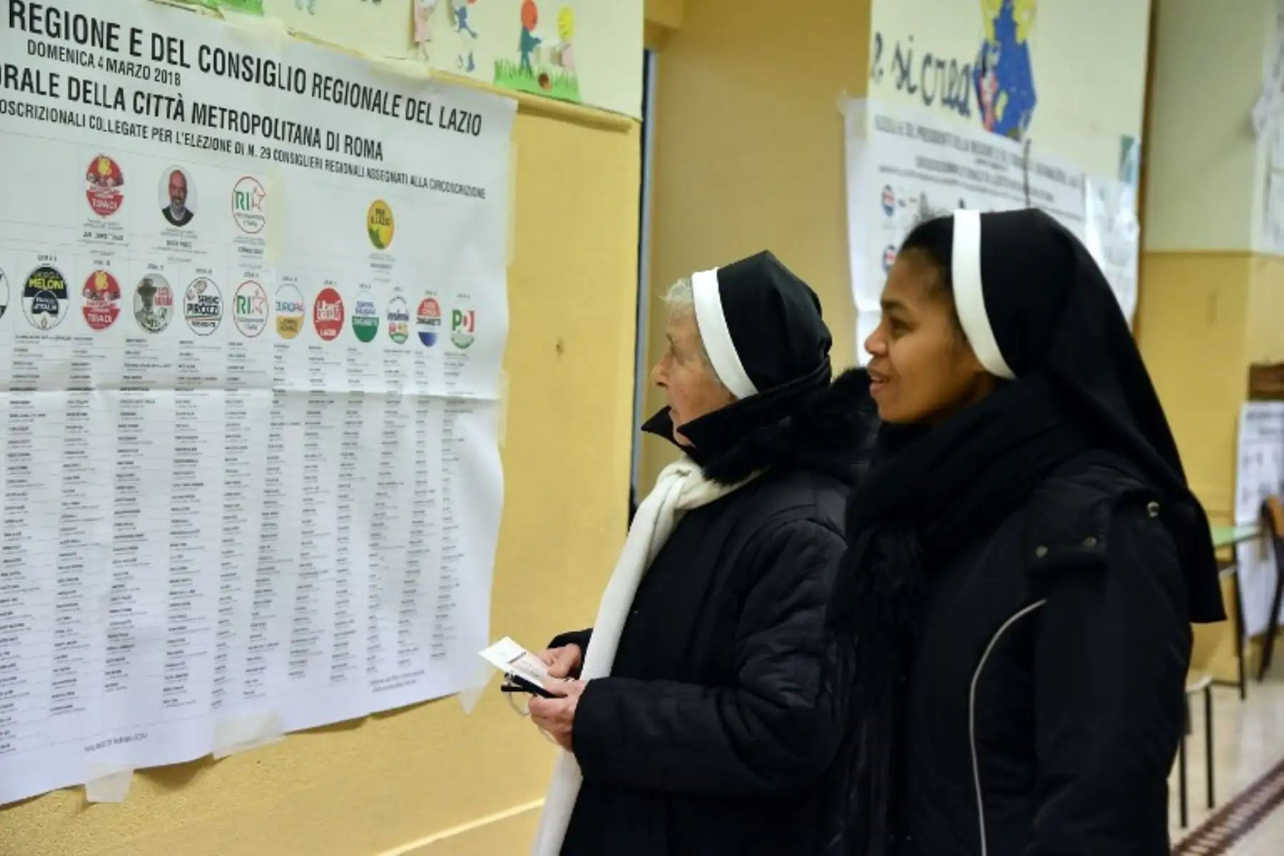 Las monjas leen un cartel que muestra los nombres de los candidatos antes de votar en una mesa de votación en Roma.Foto:AFP