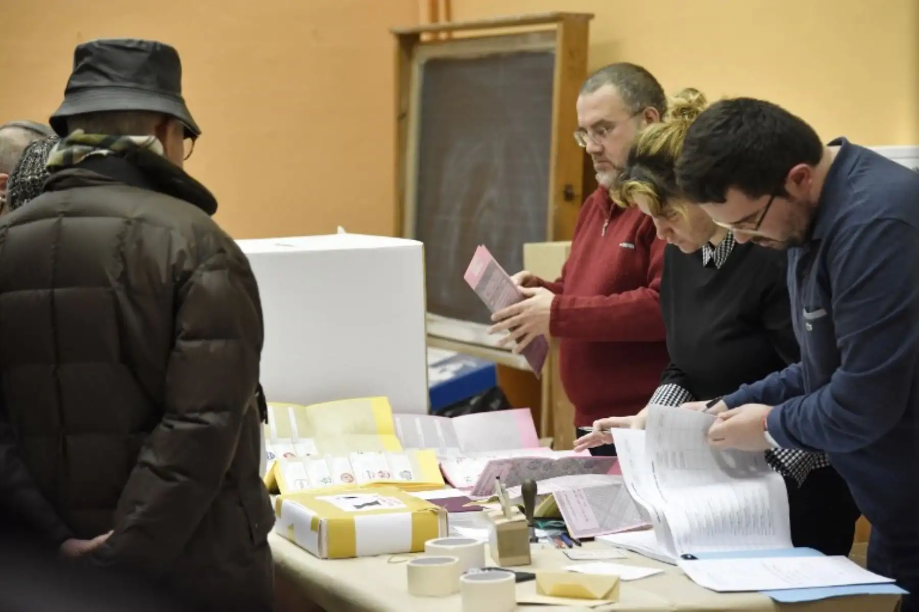 Los asesores electorales buscan el nombre de un ciudadano antes de votar, en una mesa de votación en el centro de Roma..Foto:AFP