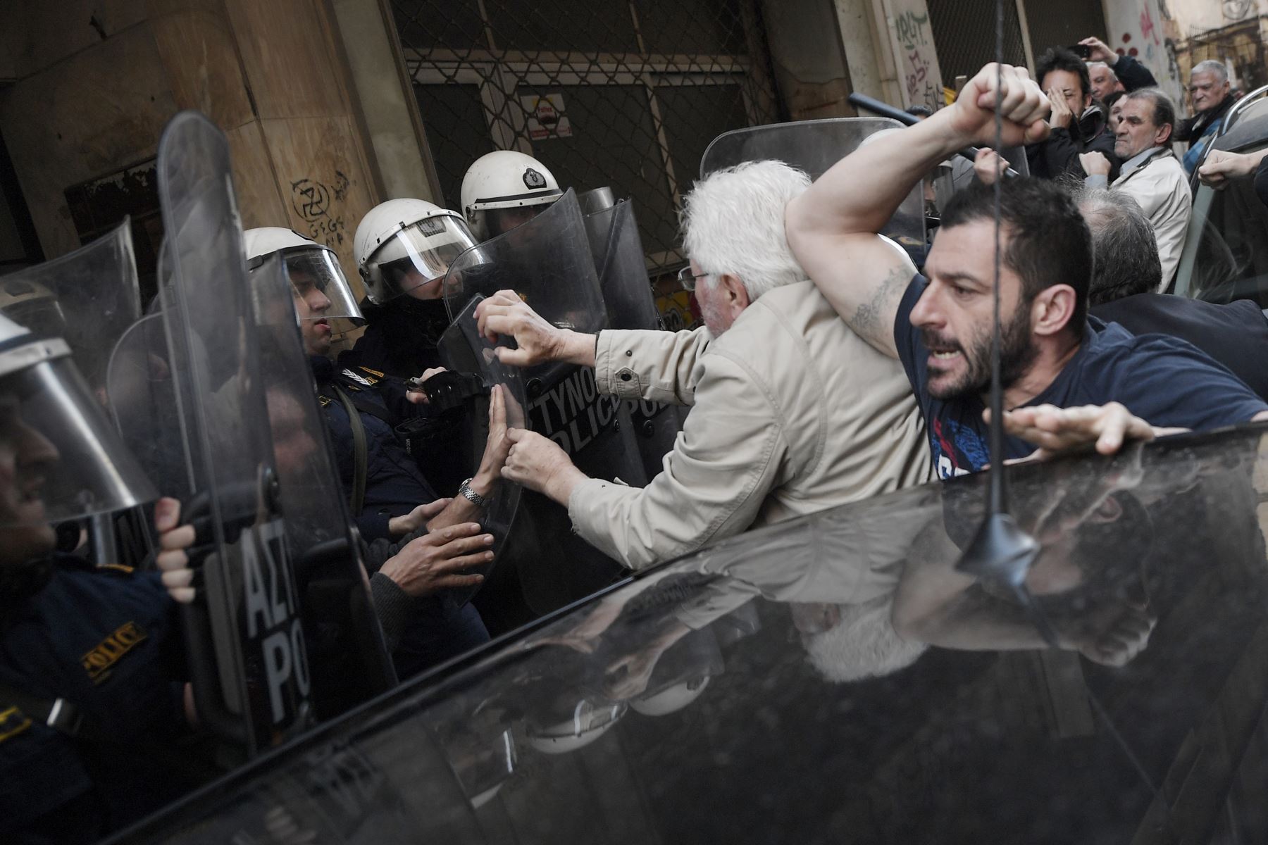 Manifestantes se enfrentan con la policía que custodia la entrada de una notaría pública en Atenas. Foto: AFP