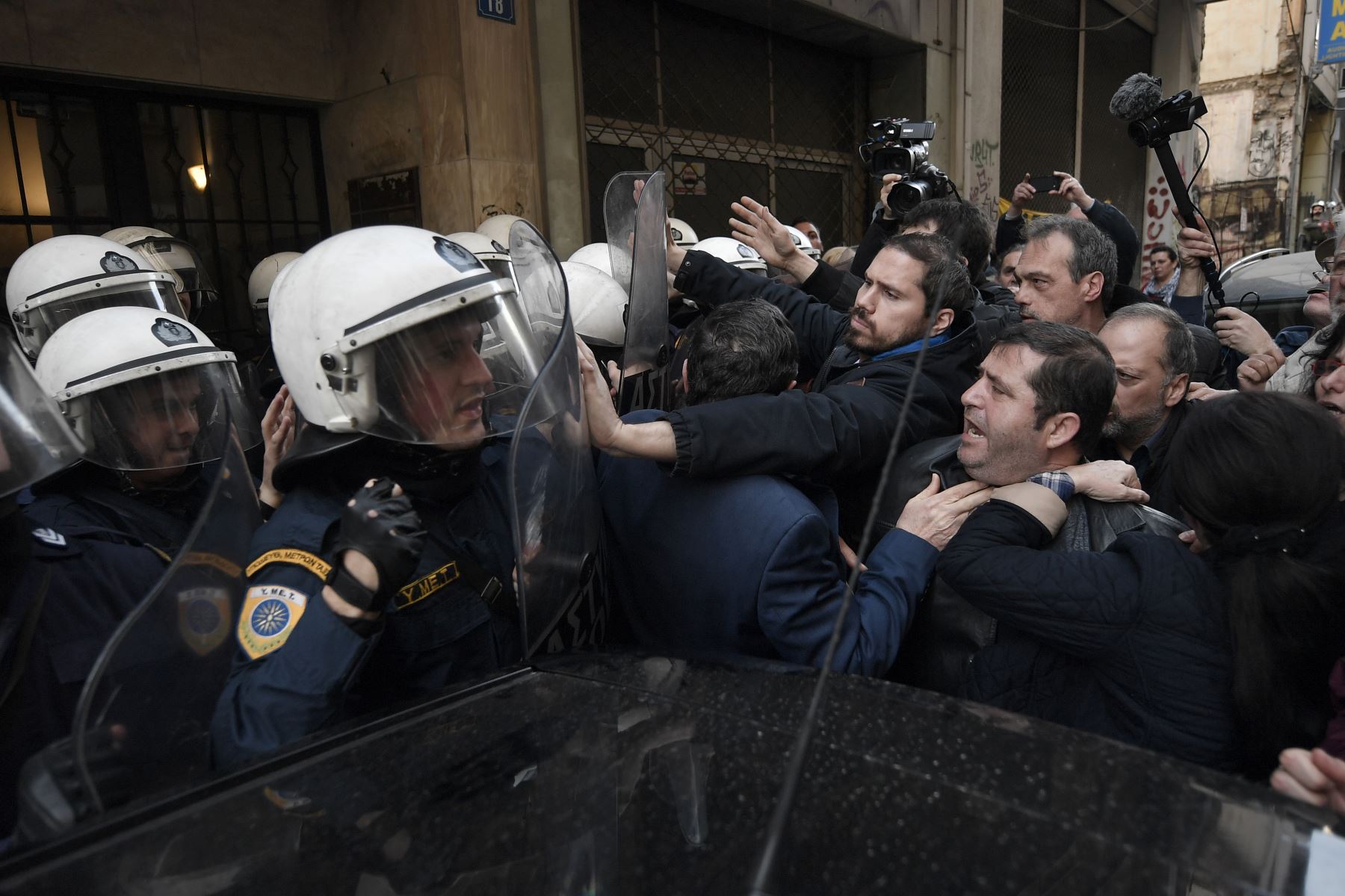 Manifestantes se enfrentan con la policía que custodia la entrada de una notaría pública en Atenas. Foto: AFP