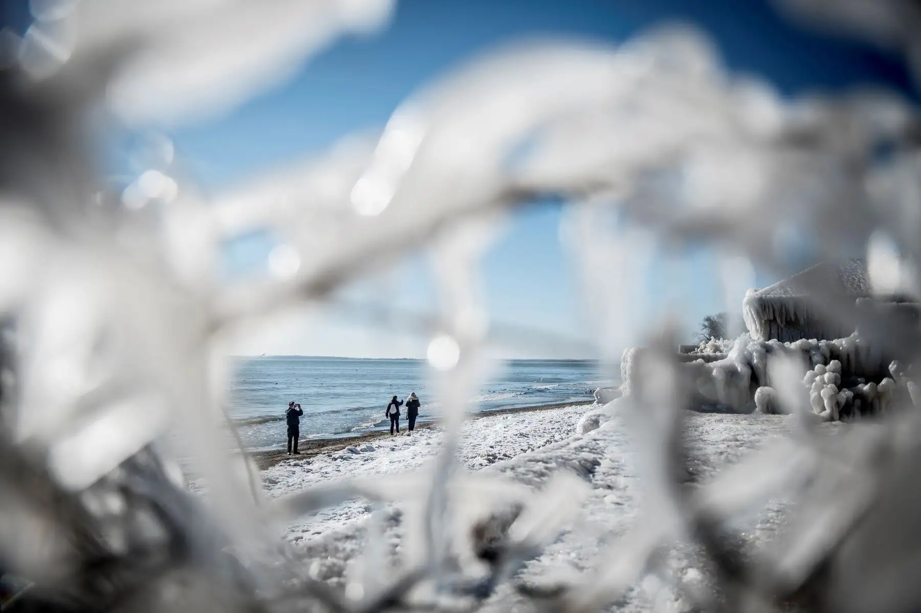Un grupo de personas caminan por la orilla junto a una casa por completo por el hielo en Faxe Bay al sur de Copenhague (Dinamarca). EFE/ Mads Claus Rasmussen