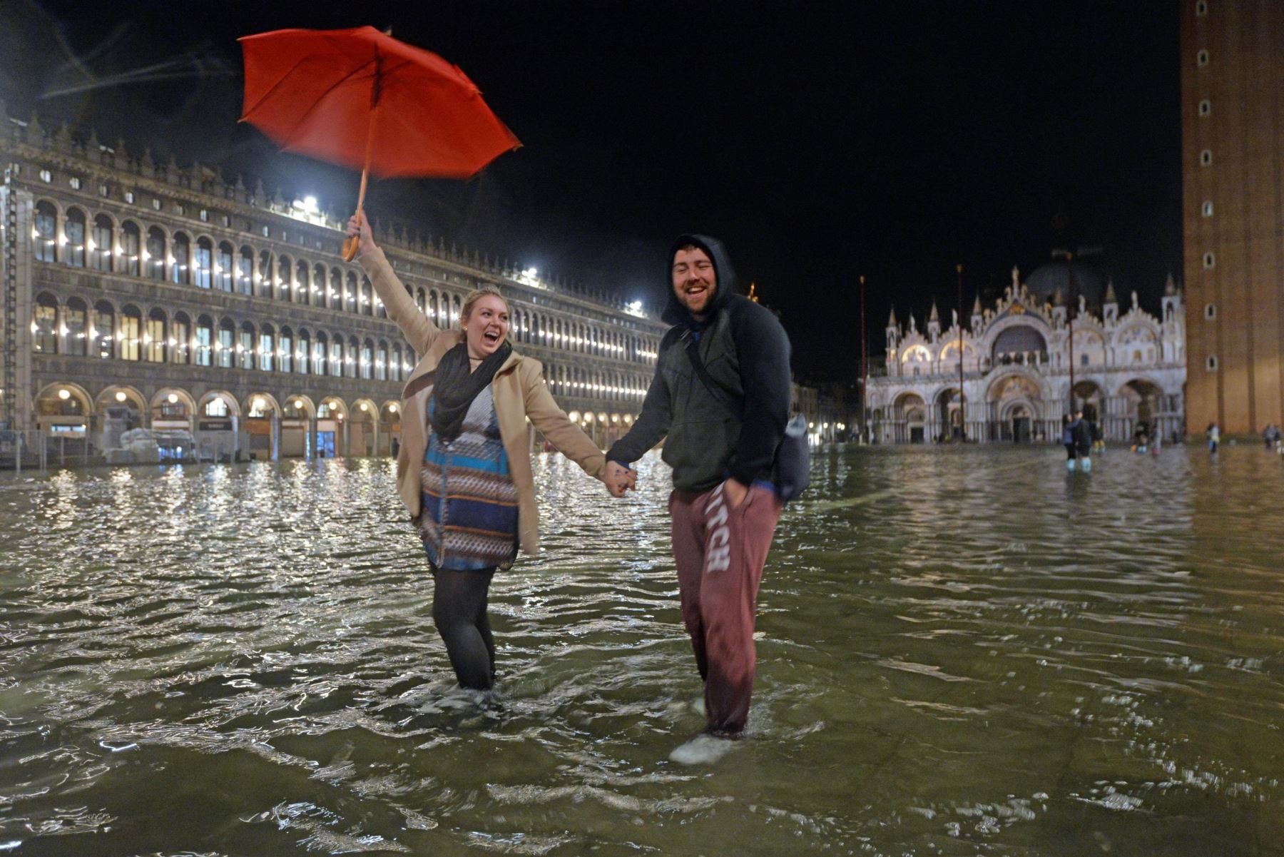 Dos turistas posan para una fotografía con los pies cubiertos de agua por las crecidas en la plaza de San Marco en Venecia. El agua llegó a 124 centímetros por encima del nivel del mar causando inundaciones en la ciudad de los canales. EFE/ Andrea Merola