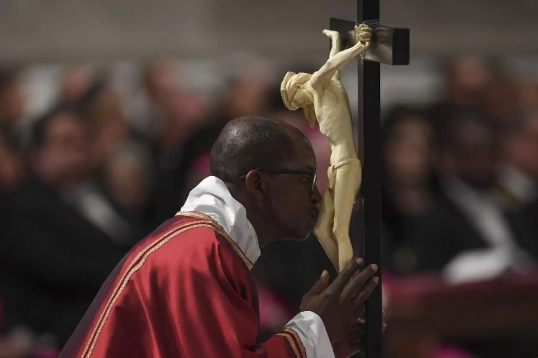 Un religioso besa un crucifijo durante la celebración de la Pasión del Señor el Viernes Santo, en la basílica de San Pedro. Foto: AFP.