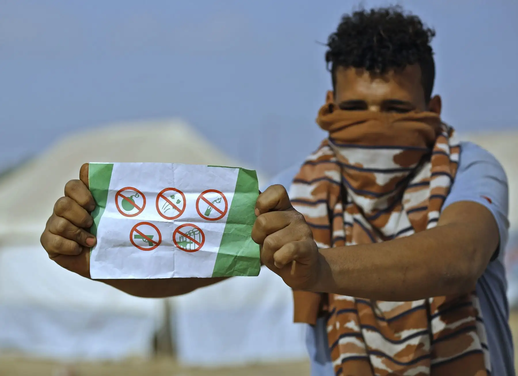 Un palestino muestra un folleto enviado por el ejército israelí sobre Gaza que pide a los residentes del territorio costero palestino que no usen ningún tipo de armas y que no se acerquen a la valla fronteriza, en el lugar de las tiendas de protesta junto a la frontera de la Franja de Gaza Israel. Foto: AFP