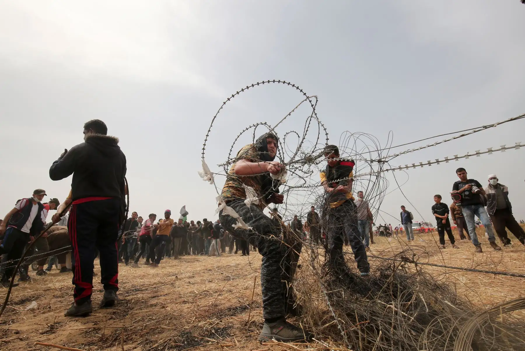 Los manifestantes palestinos sacan alambre de púas de la valla fronteriza con Israel, en Rafah, Franja de Gaza. AFP