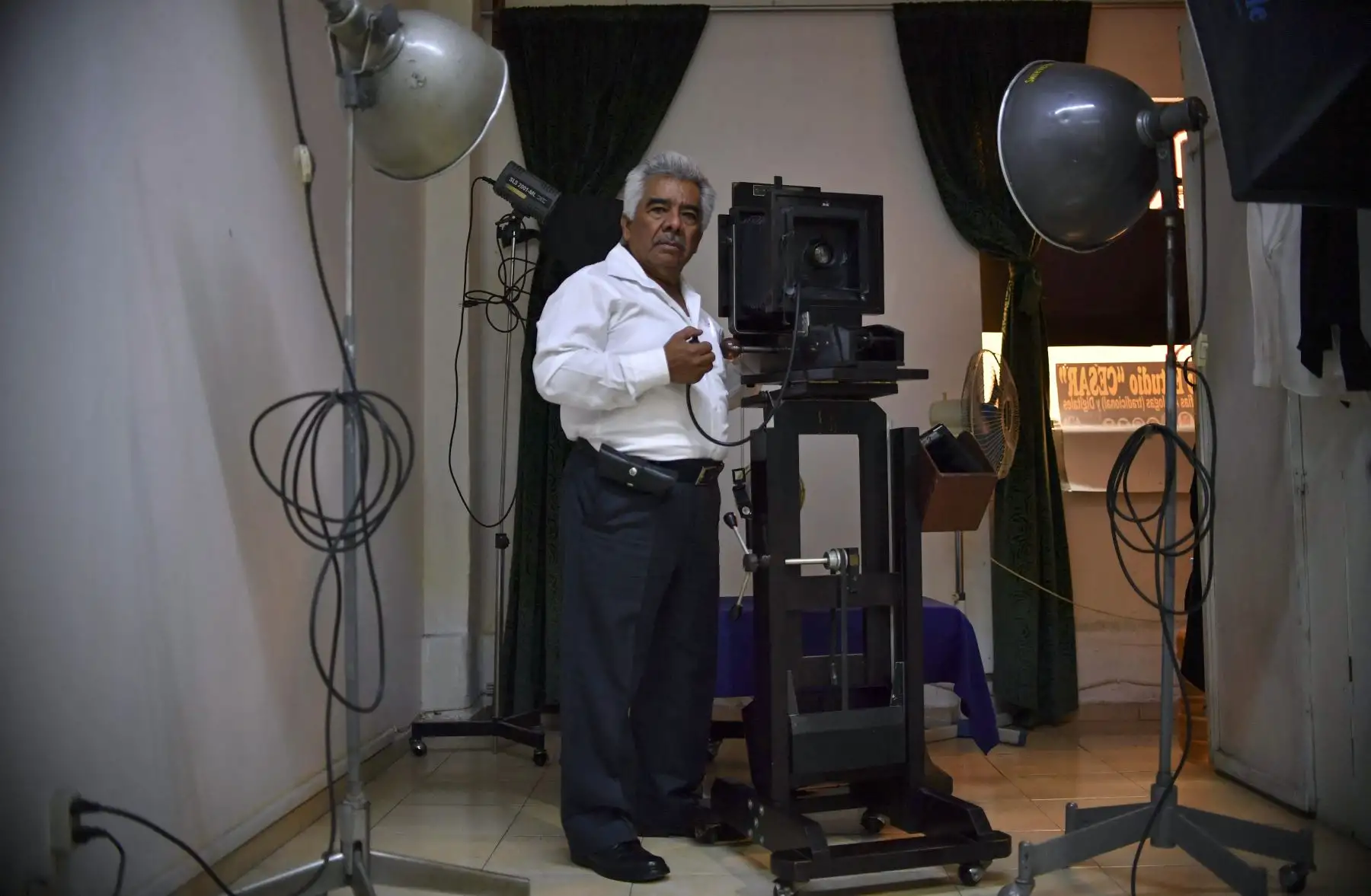 El fotógrafo Cesar Arizmendi, de 73 años, posa para una foto en su estudio con su cámara de cajón artesanal diseñada por él mismo, en la Ciudad de México. Foto: AFP