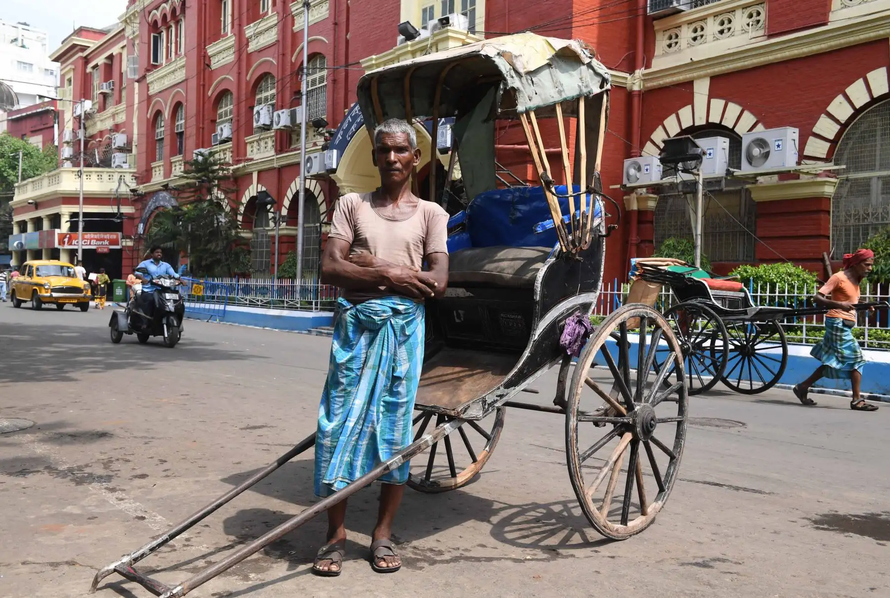 Mohammad Ashgar, de 65 años, un tirador de rickshaw indio, posa para una fotografía junto a su rickshaw en Calcuta. Foto: AFP