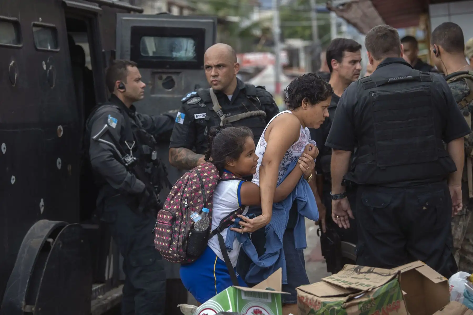 Una madre lleva a su hijo a un lugar seguro durante un operativo de la Policía Militar en la favela Ciudad de Dios en Río de Janeiro, Brasil. Foto: AFP