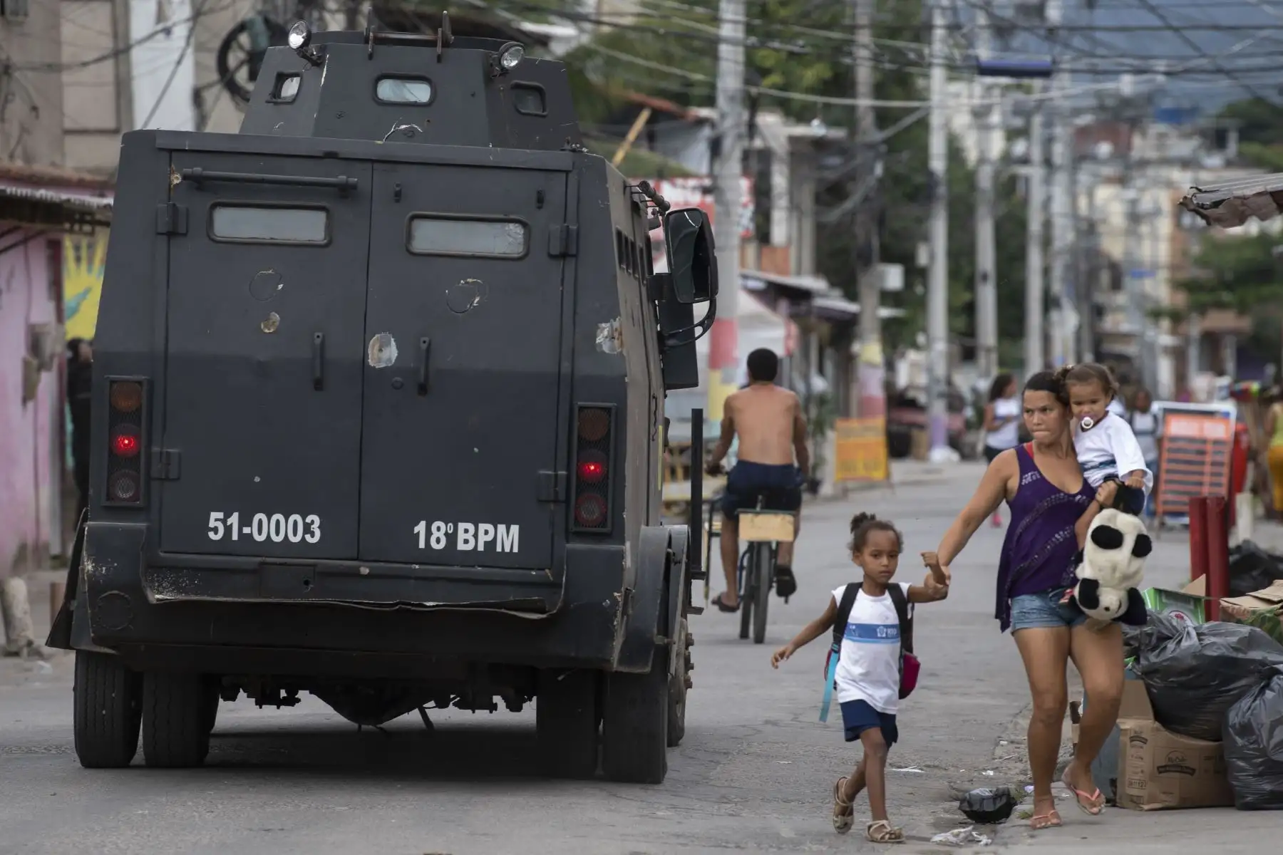 Una madre lleva a su hijo a un lugar seguro durante un operativo de la Policía Militar en la favela Ciudad de Dios en Río de Janeiro, Brasil. Foto: AFP