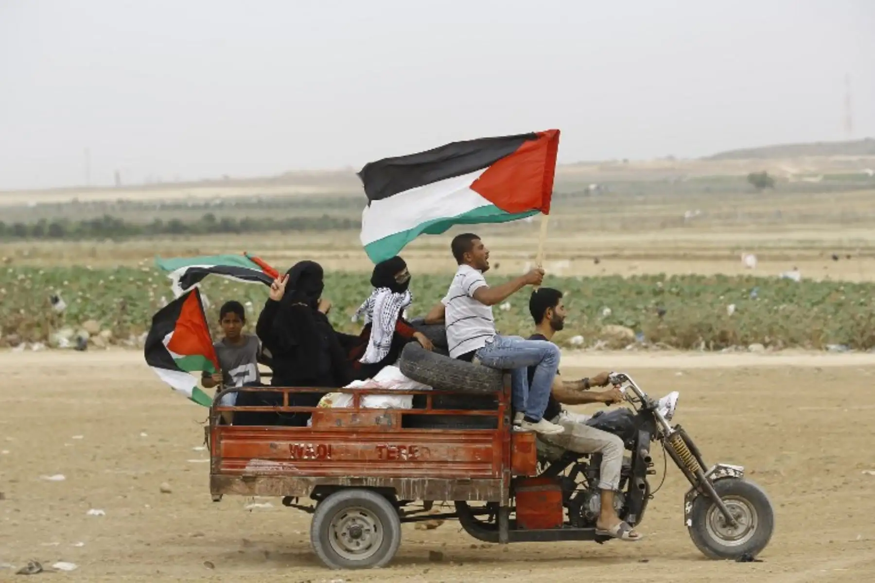 Manifestantes palestinos con banderas nacionales, transportan neumáticos para quemarlos durante las protestas cerca de la valla fronteriza entre Israel y la Franja de GazaFoto:AFP