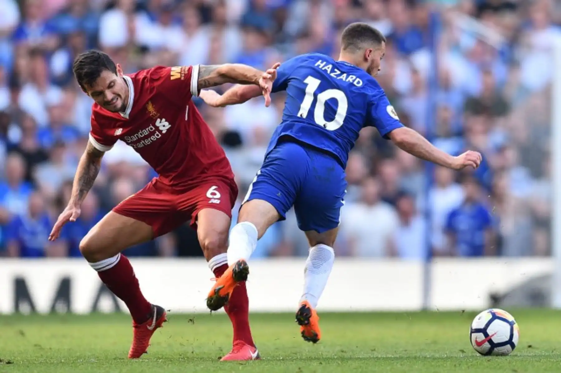 El defensa croata del Liverpool Dejan Lovren compite con el mediocampista belga Chelsea Hazard del Chelsea, durante el partido de fútbol de la Liga Premier inglesa. Foto: AFP.