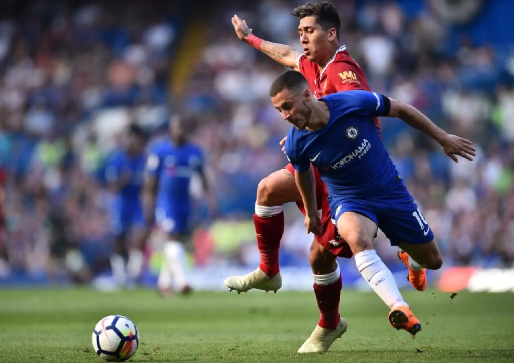 El centrocampista belga del Chelsea Eden Hazard compite con el centrocampista brasileño del Liverpool Roberto Firmino durante el partido de fútbol de la Liga Premier inglesa. Foto: AFP.