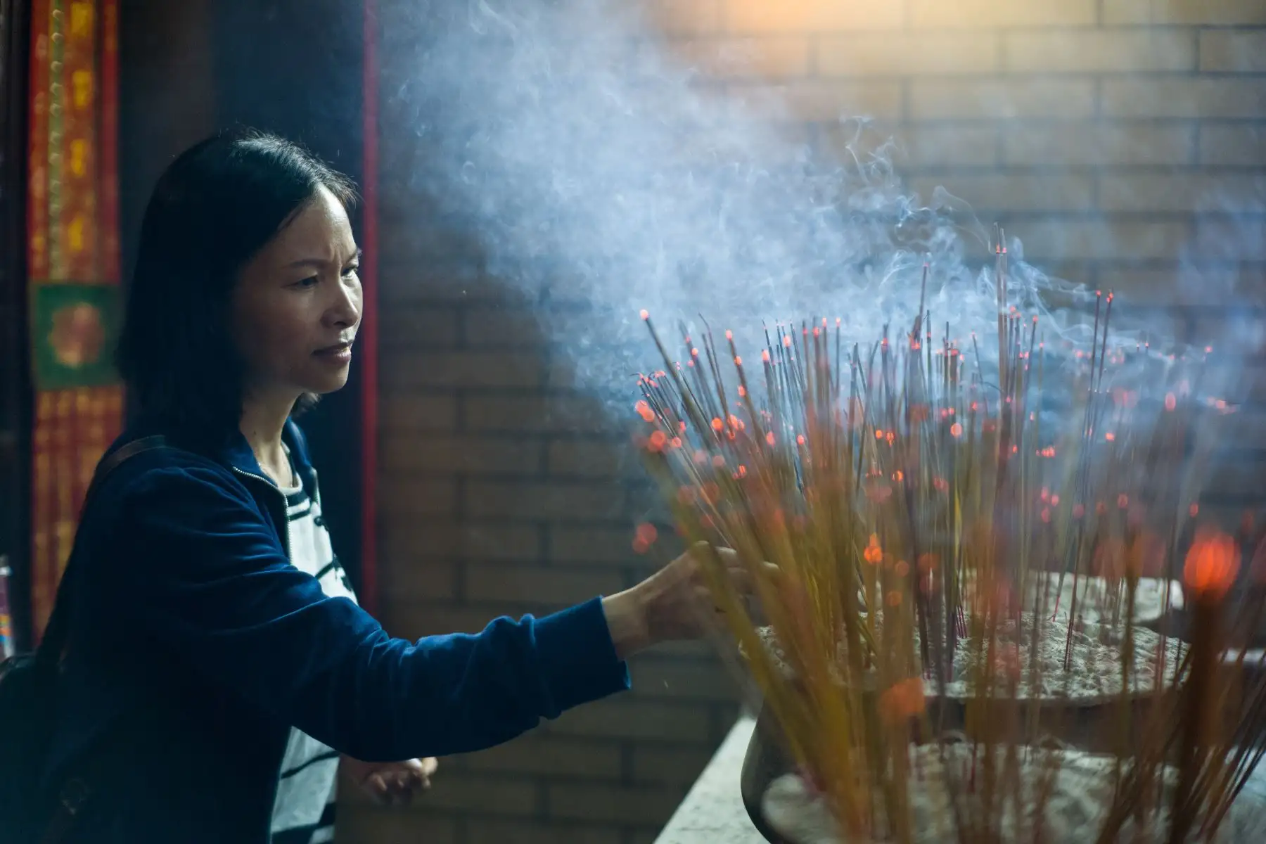 Una mujer ofrece joss sticks mientras celebra el Tin Hau Festival en el Tai Shu Ha. AFP