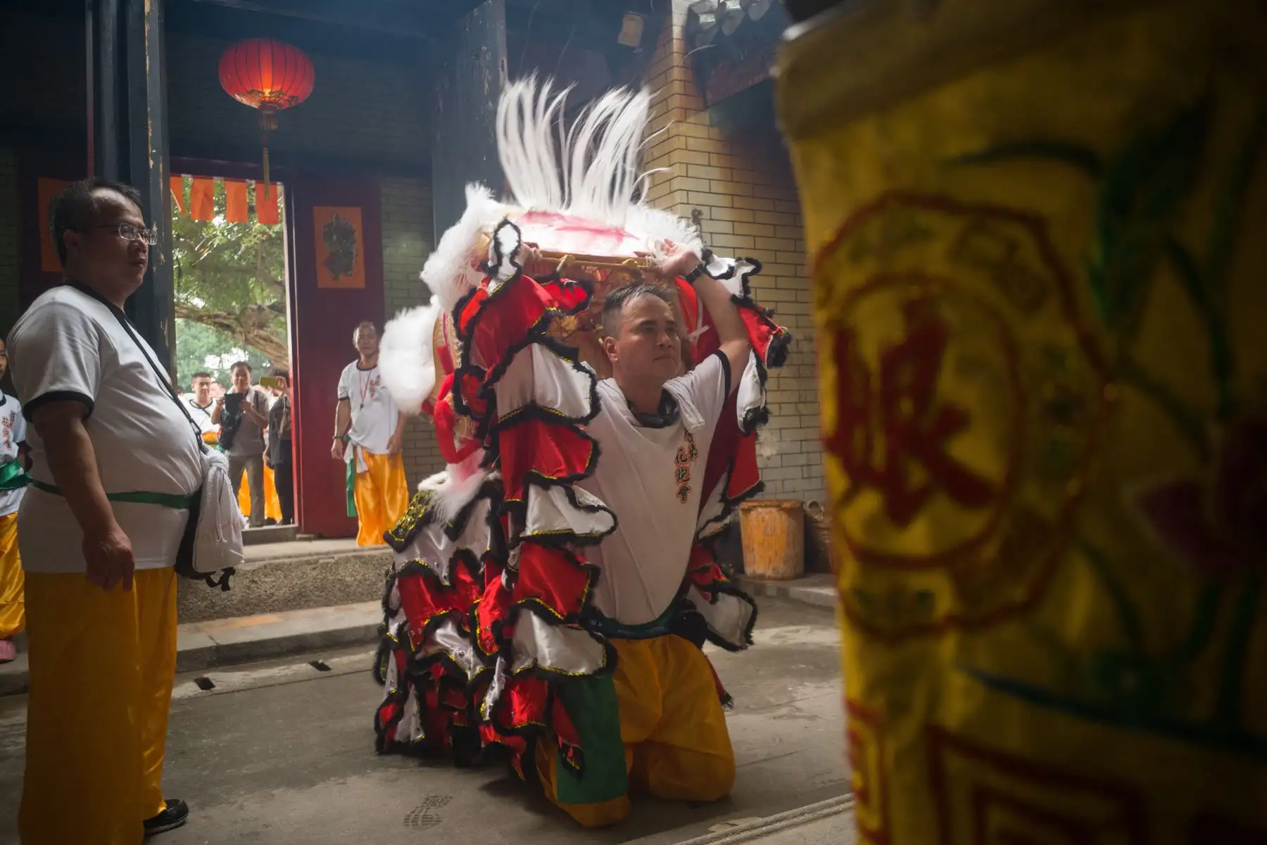 Un miembro de una compañía de danza del león levanta su máscara mientras se arrodilla frente a un altar para celebrar el Festival de Tin Hau. AFP