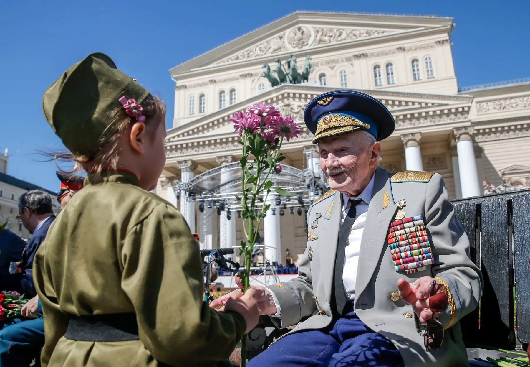 Un niño presenta una flor a un veterano de la Segunda Guerra Mundial frente al Teatro Bolshoi durante las celebraciones del Día de la Victoria en el centro de Moscú. AFP