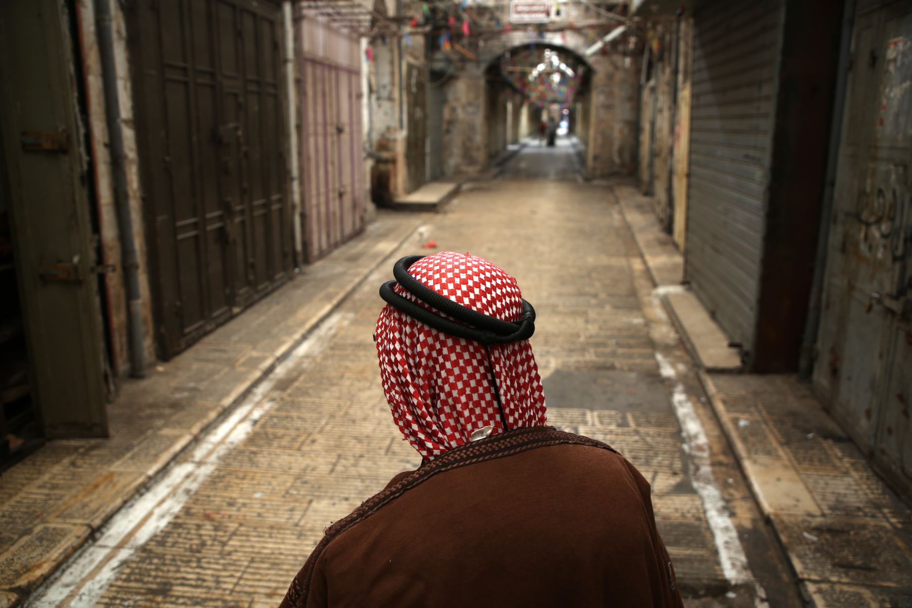 Un palestino pasa frente a tiendas cerradas en una calle vacía en la ciudad ocupada israelí de Nablus, en Cisjordania, durante una huelga general convocada por líderes solidarios con Gaza y en protesta contra el traslado de la embajada de Estados Unidos a Jerusalén. AFP