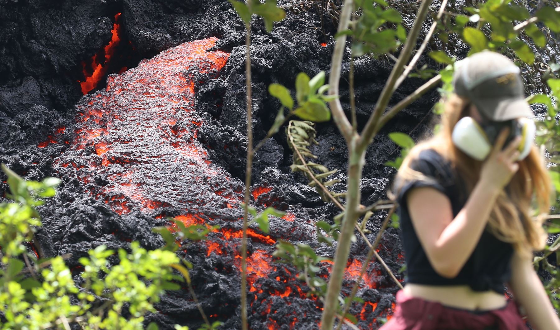 La lava fluye en una nueva fisura después de las erupciones del volcán Kilauea, en la isla grande de Hawái, cuando un residente local camina cerca después de tomar fotos. Foto: AFP.