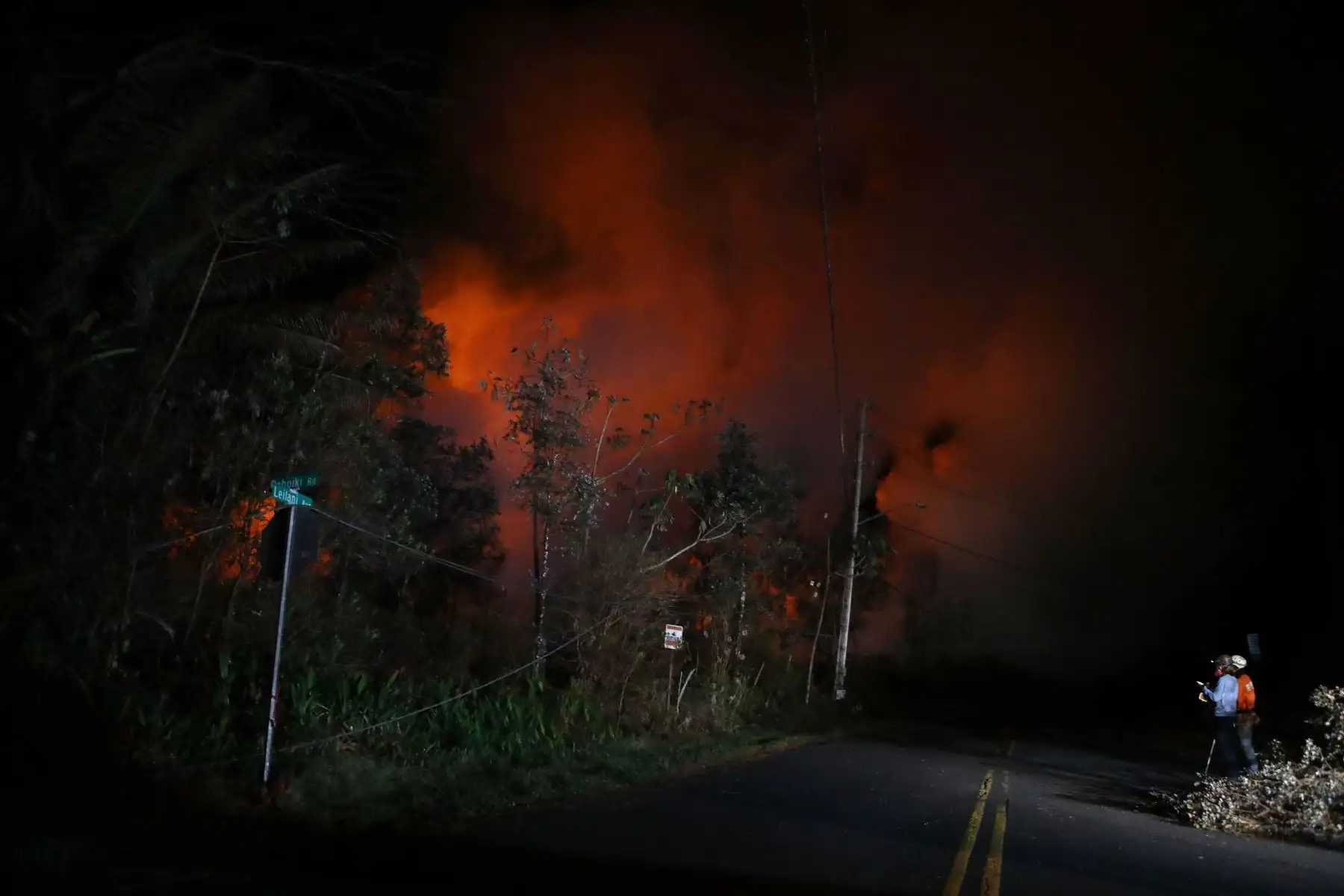 Geólogos estudian la lava que ilumina los gases volcánicos del volcán Kilauea, en la fisura 13 en la isla grande de Hawái. Foto: AFP.