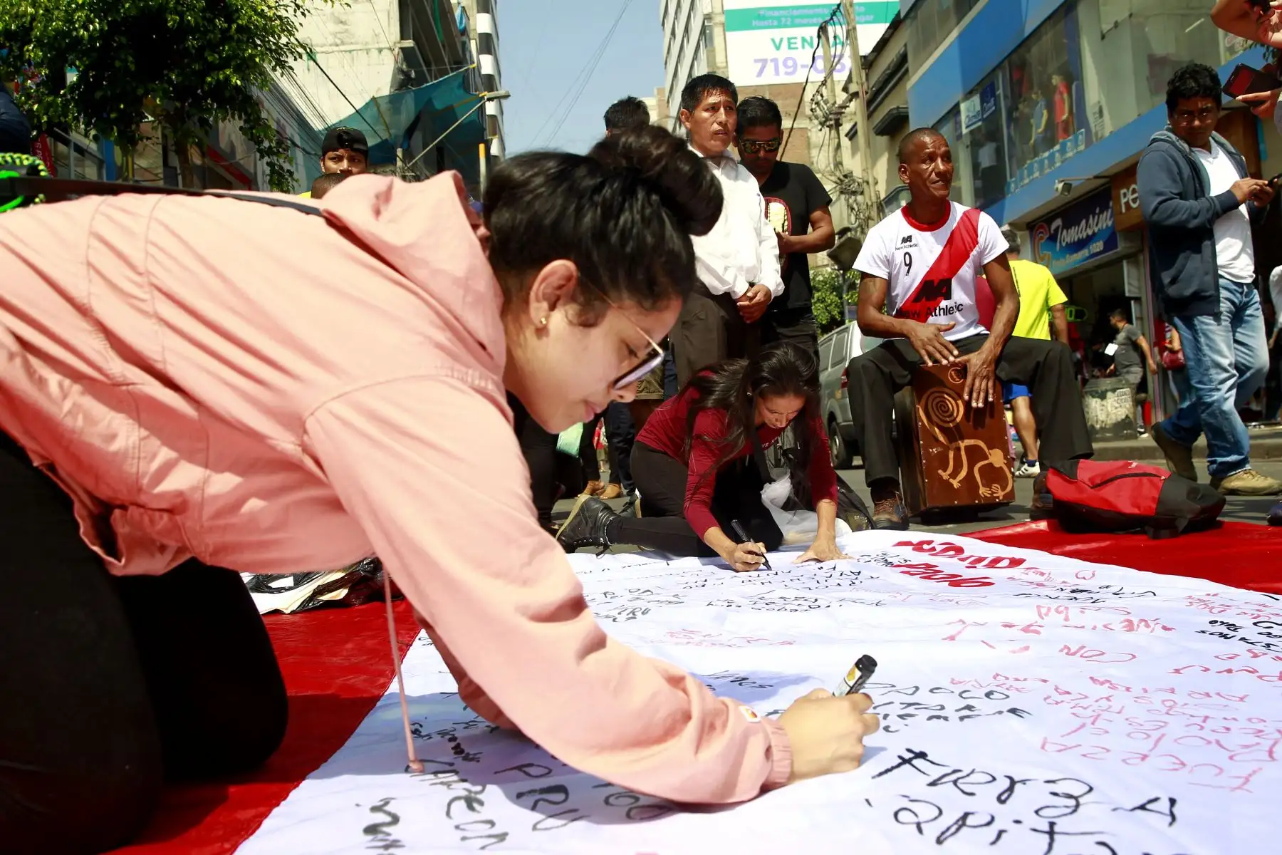 Hinchas firman “Bandera Guerrera”, confeccionada por los comerciantes de Gamarra. Foto: ANDINA/Eddy Ramos.