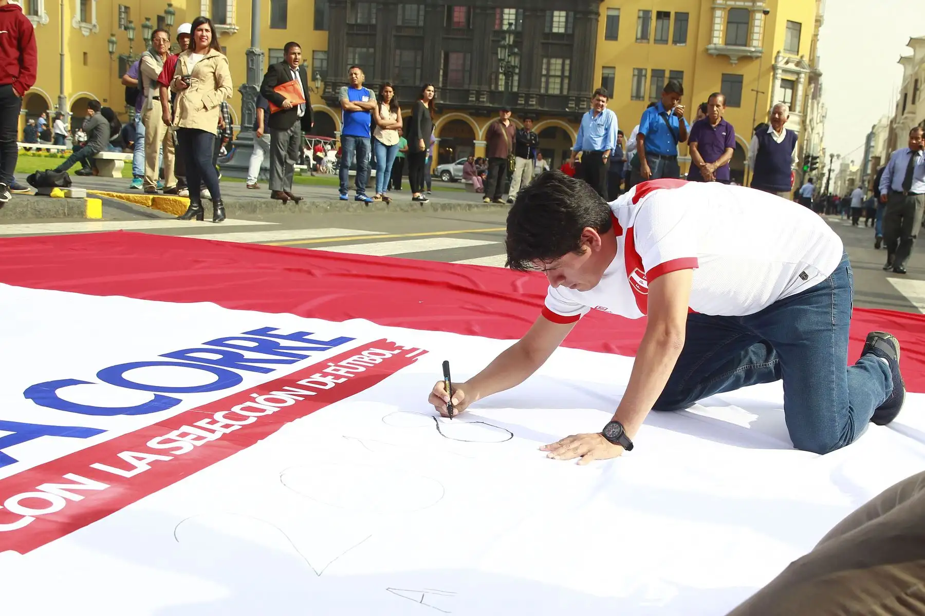 Hinchas peruanos participan en "Banderazo por la Blanquirroja" en la Plaza Mayor, donde las personas dejan un mensaje de aliento a la selección en una bandera gigante. Foto: ANDINA/Eddy Ramos.