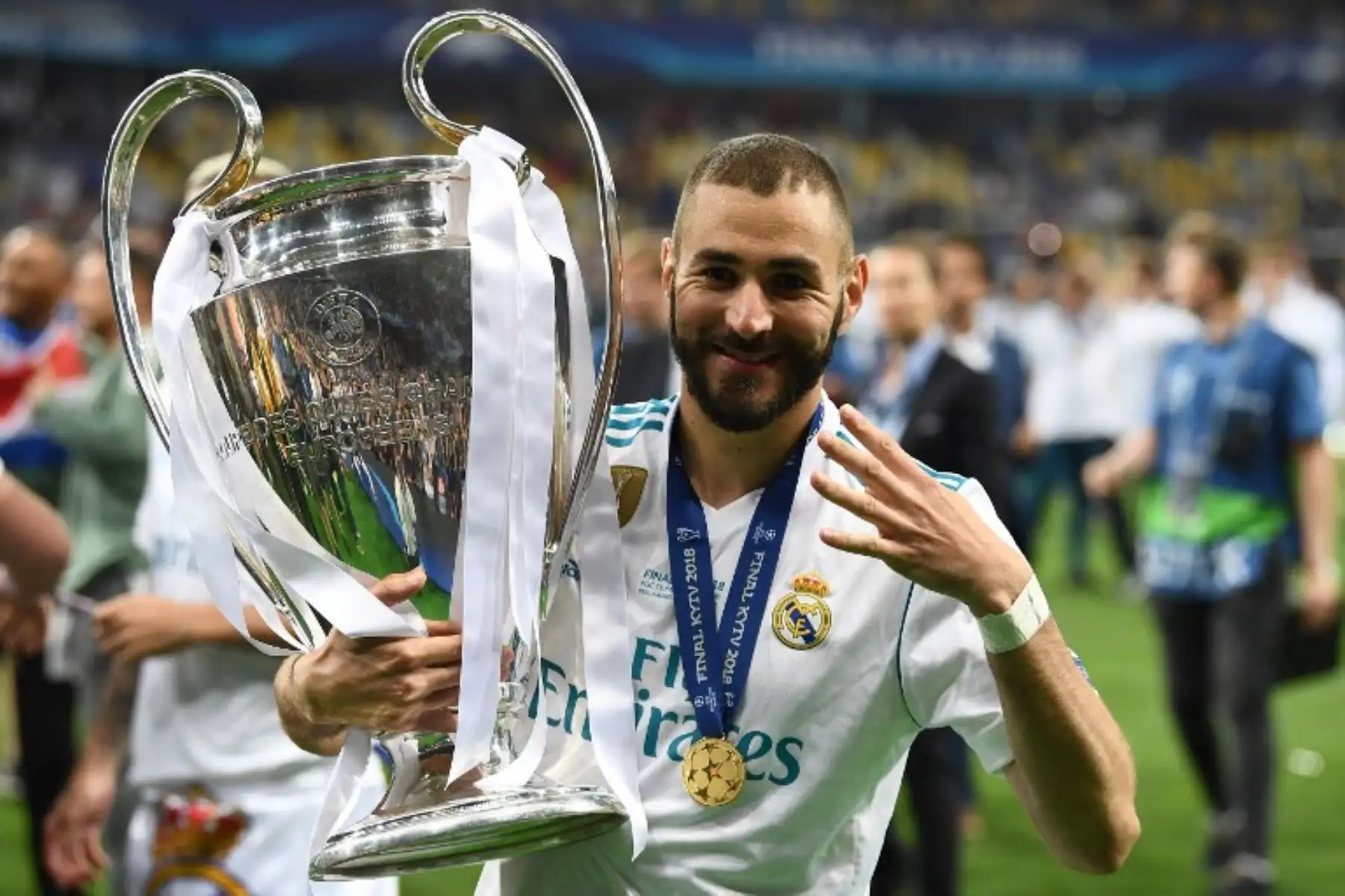 El delantero francés del Real Madrid Karim Benzema gesticula el número cuatro mientras posa con el trofeo después de ganar la UEFA