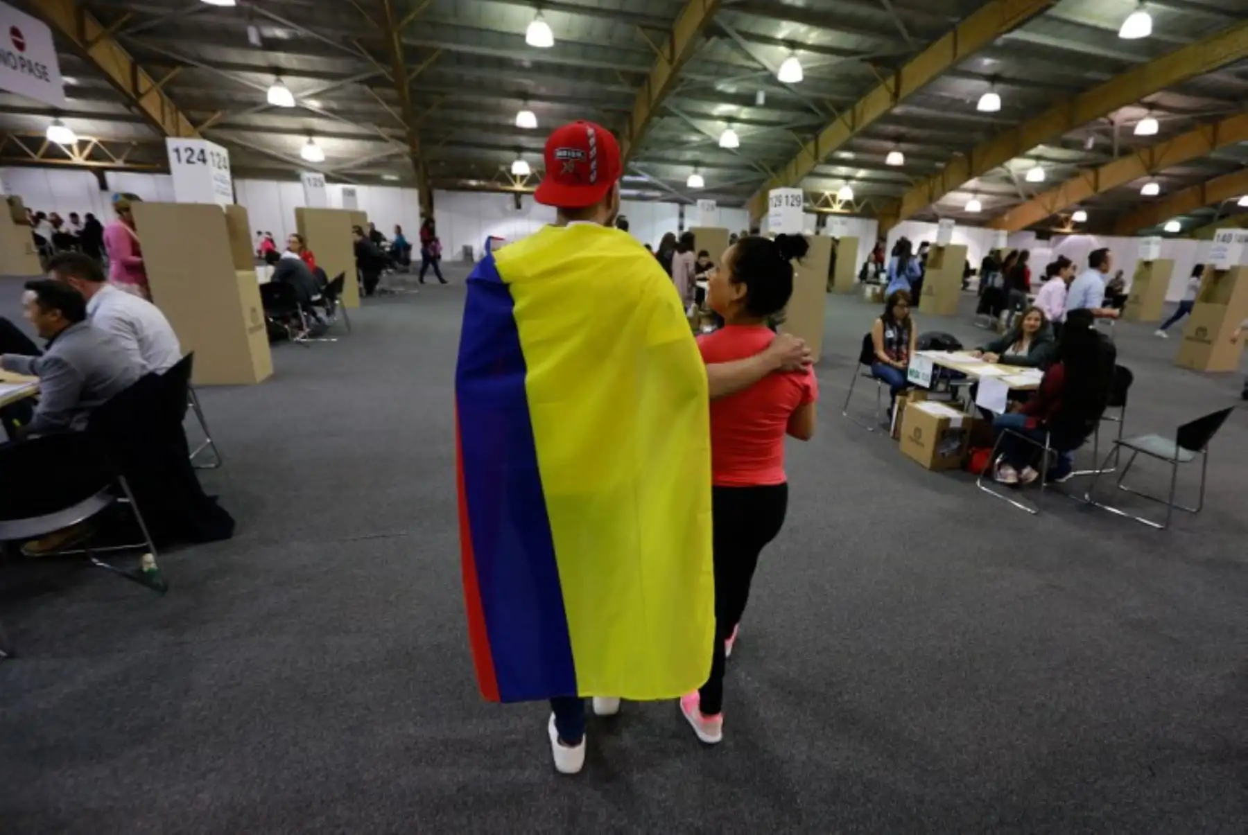 Un votante envuelto en una bandera nacional colombiana es visto en una mesa electoral en Bogotá durante la primera vuelta de las elecciones presidenciales en Colombia.Foto:AFP